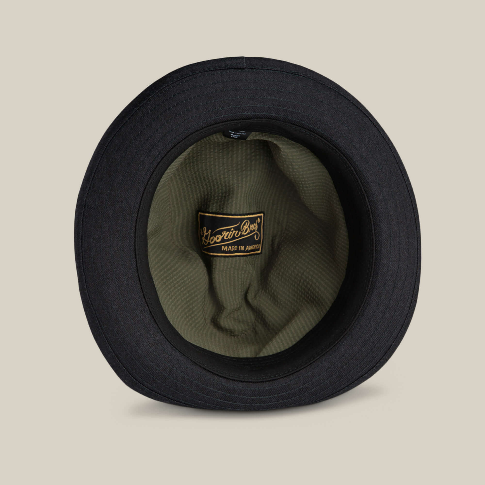 The Goorin Bros. Big Stepper is a black bucket hat seen from above, featuring an olive green inner lining and a "Made in America" label—making it a stylish accessory for any outfit.