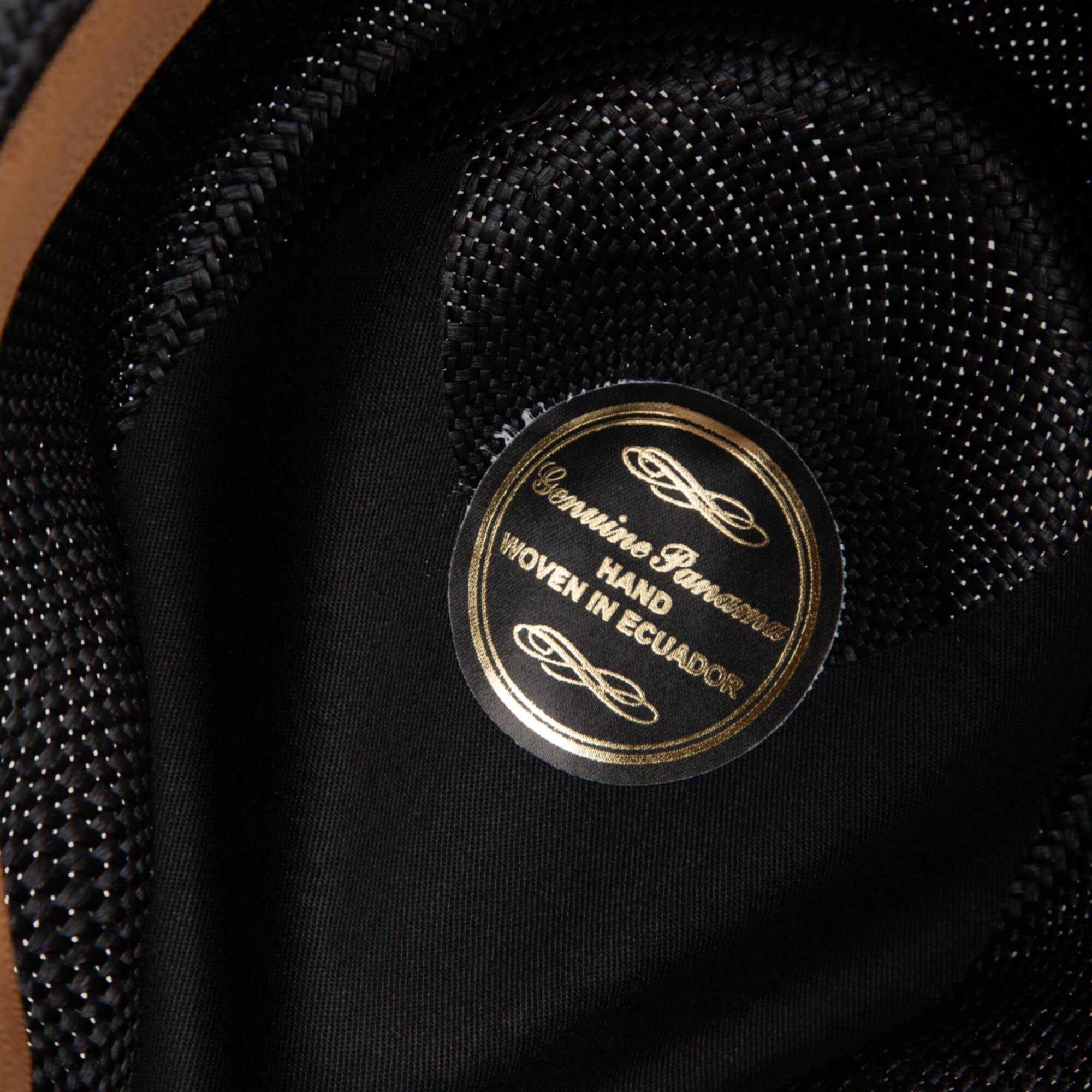 Close-up of the John Sr. hat’s inner label from Goorin Bros., reading Genuine Panama, Hand Woven in Ecuador on a black fabric background, highlighting its 50 UPF sun protection.