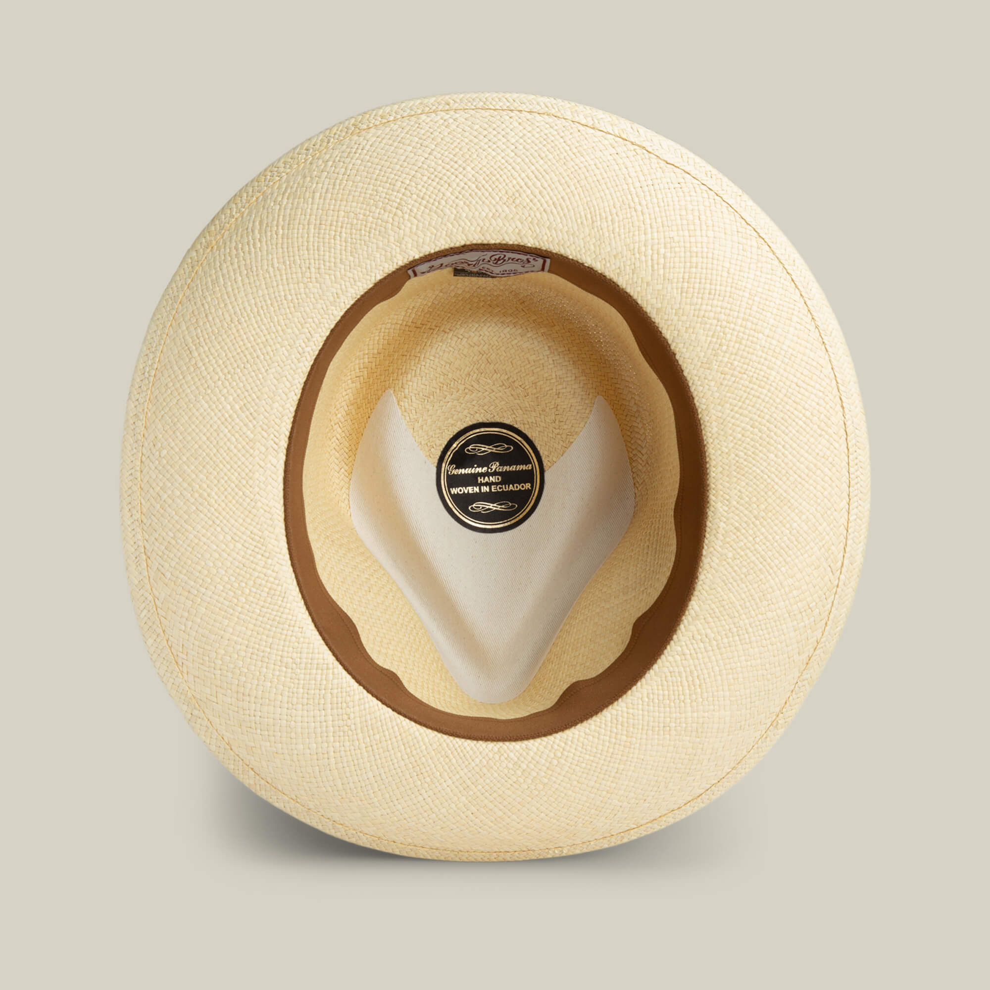 A top-down view of the Goorin Bros. John Sr. beige toquilla fedora, featuring a brown inner band, inside label, and built-in UPF 50 sun protection.