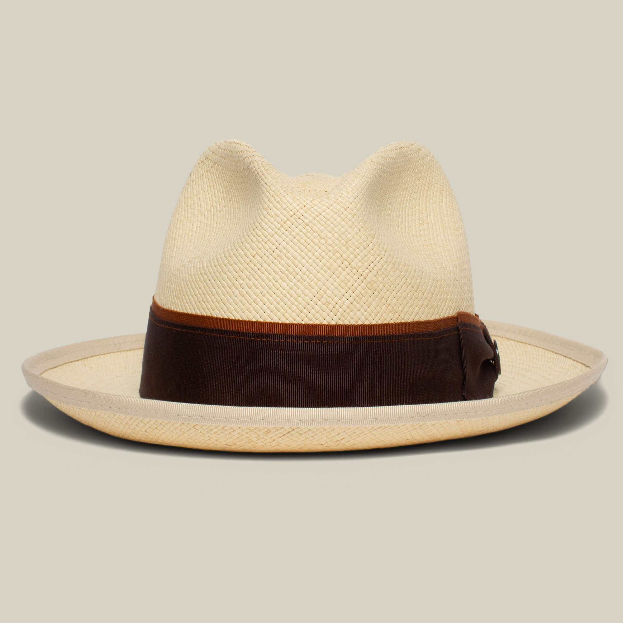 The Hartman by Goorin Bros. is a beige straw fedora with a wide brim, contrast edge binding, and a dark brown grosgrain hat band, shown against a neutral background.