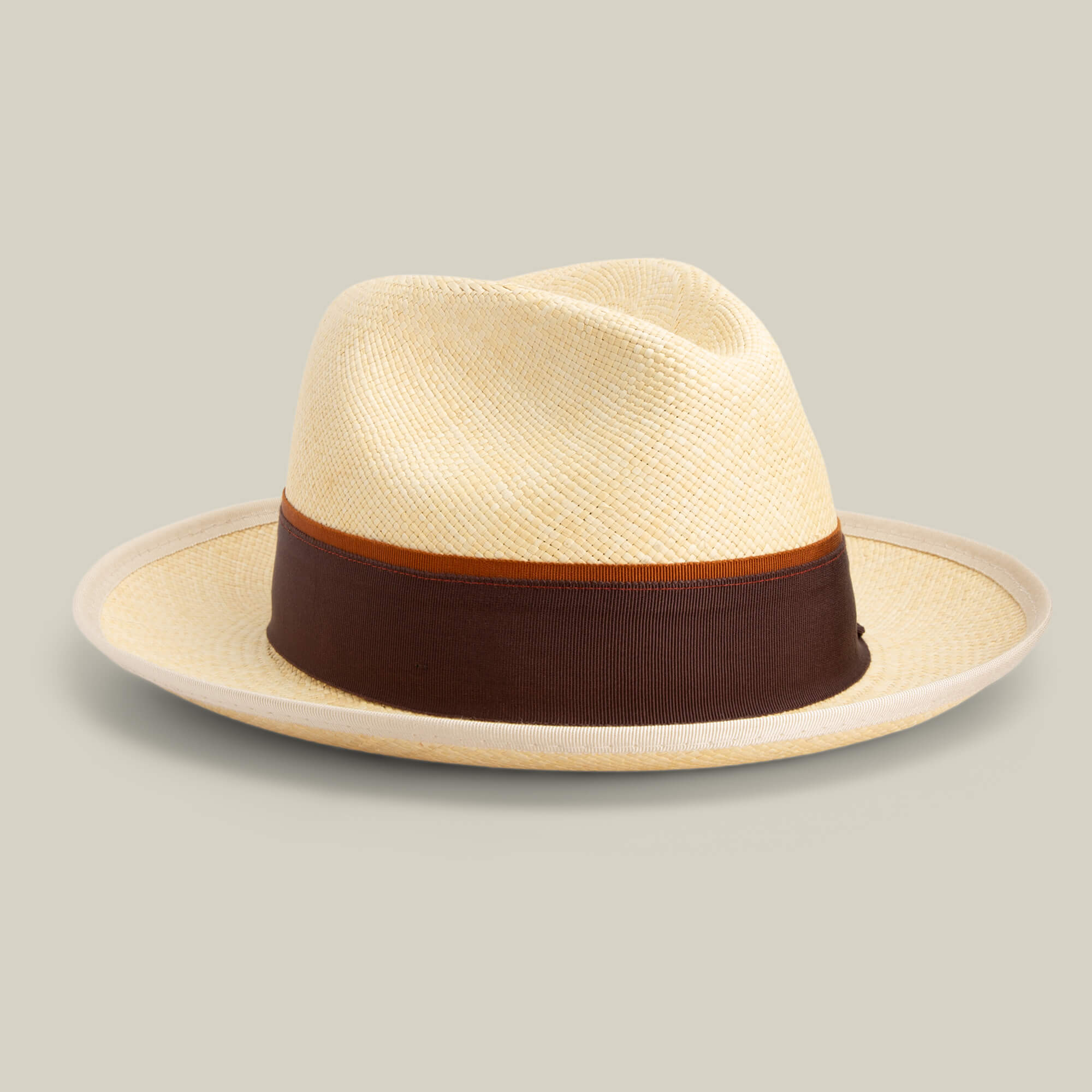 The Goorin Bros. Hartman is a beige straw fedora with a wide brown grosgrain band and contrast edge binding, shown on a light gray background. Offers 50 UPF sun protection for stylish, everyday wear.