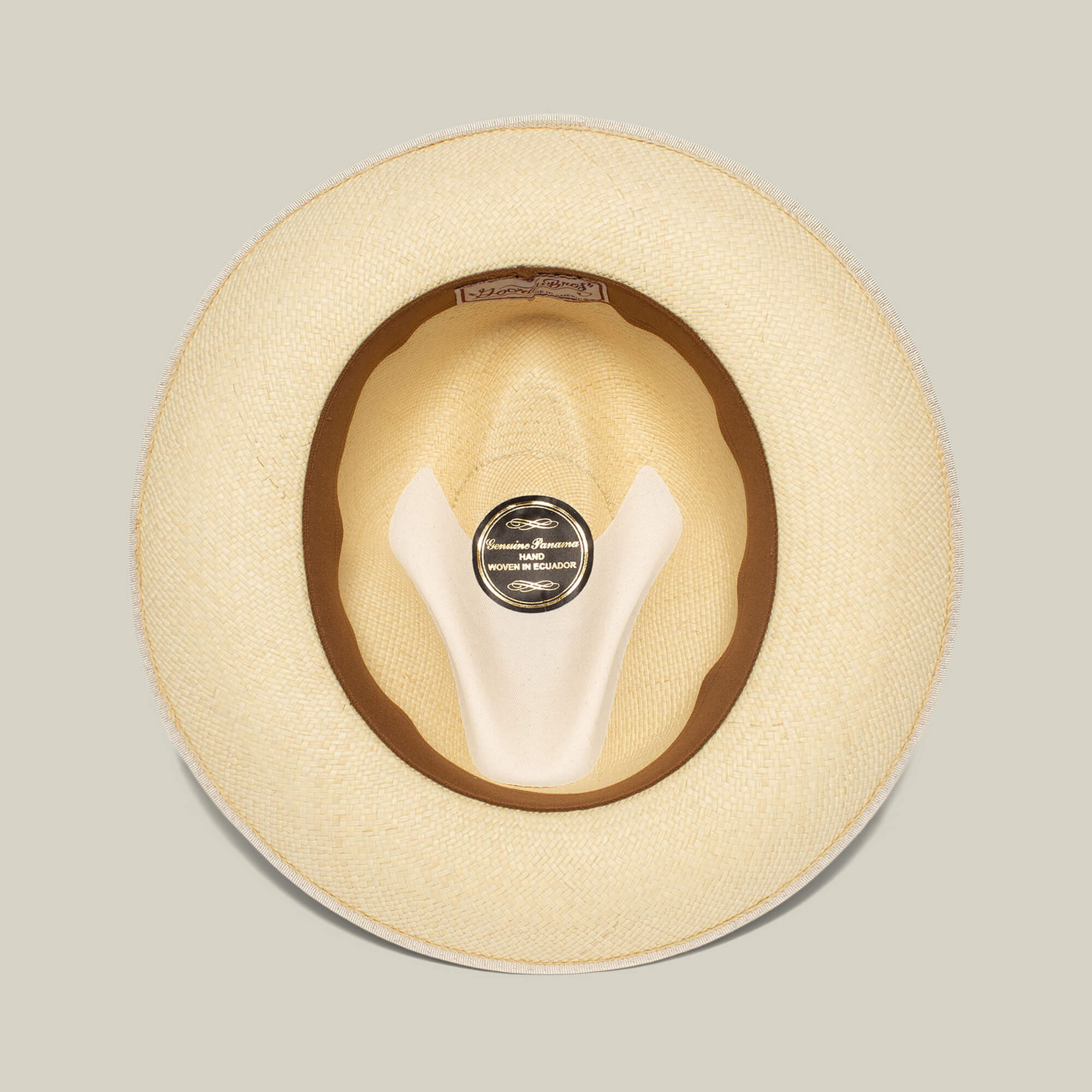 A top-down view of the Hartman straw hat by Goorin Bros., showcasing its interior crown, brown grosgrain hat band, and a black label with white text at the center.