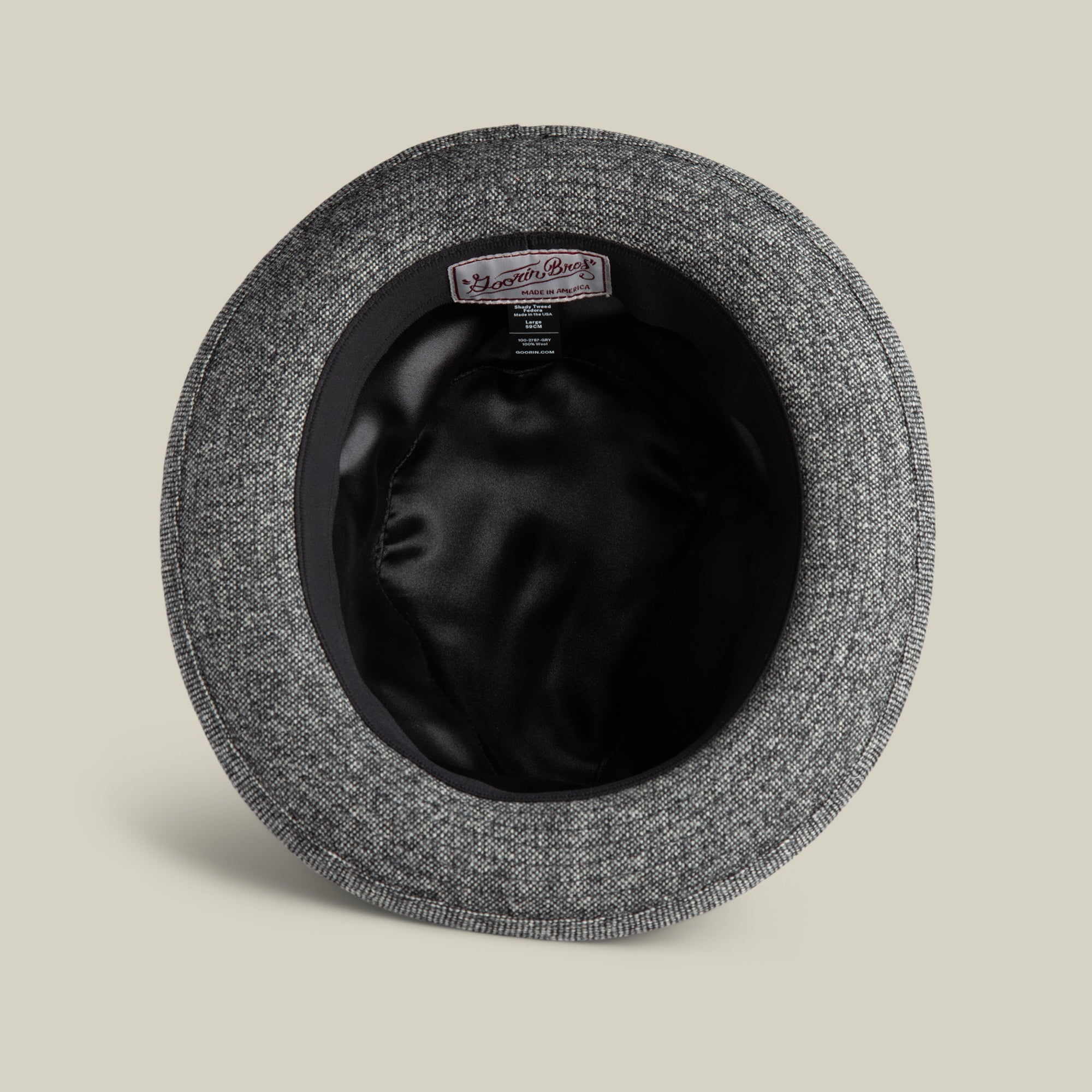 A top-down view of the inside of a grey textured Goorin Bros. Shady Tweed Fedora, featuring a black satin lining and a Moon Mill England label on the inner band.