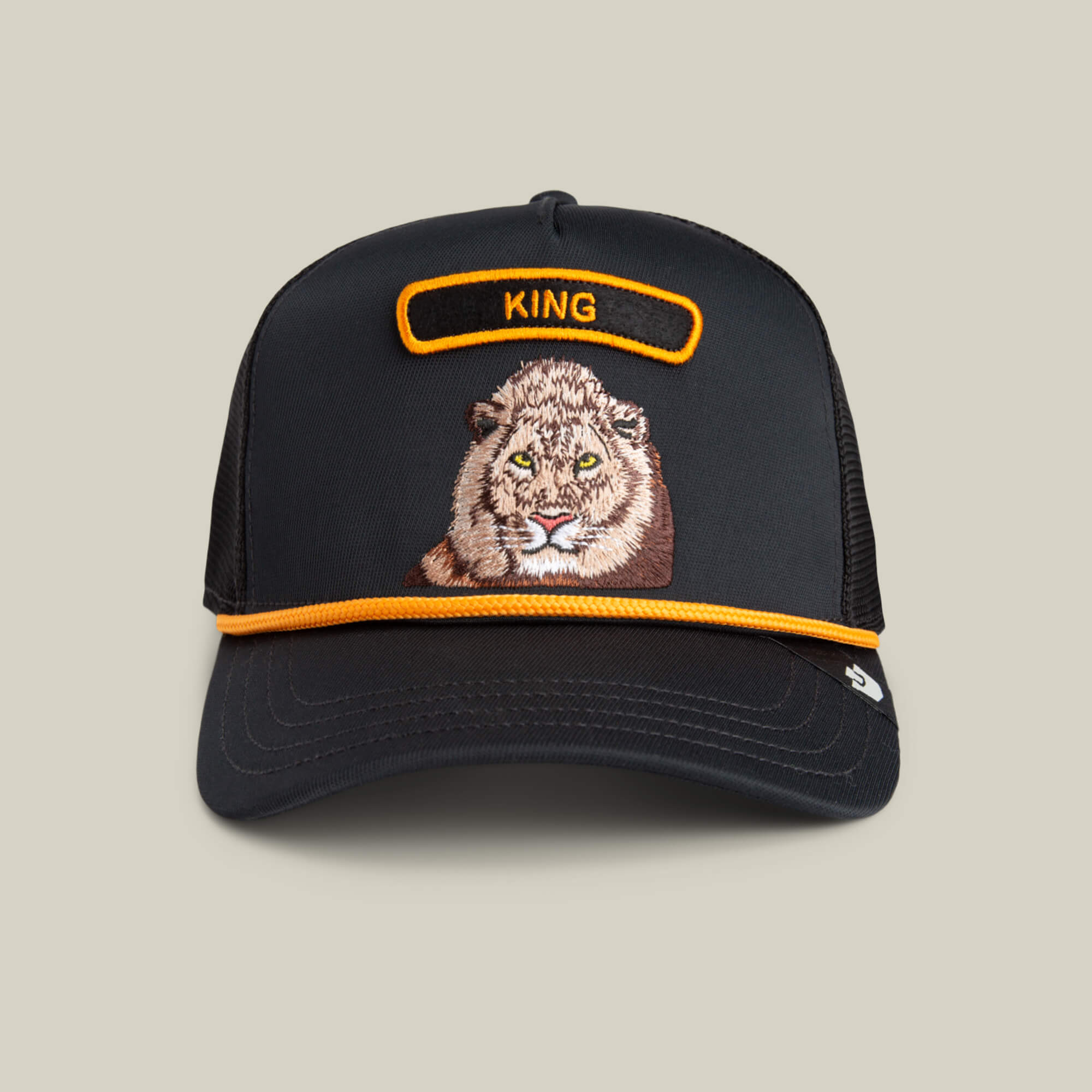 The GB2 Lion by The Farm is a black trucker hat with an embroidered lion face, orange trim, and "KING" above the lion—symbolizing strength and speed.