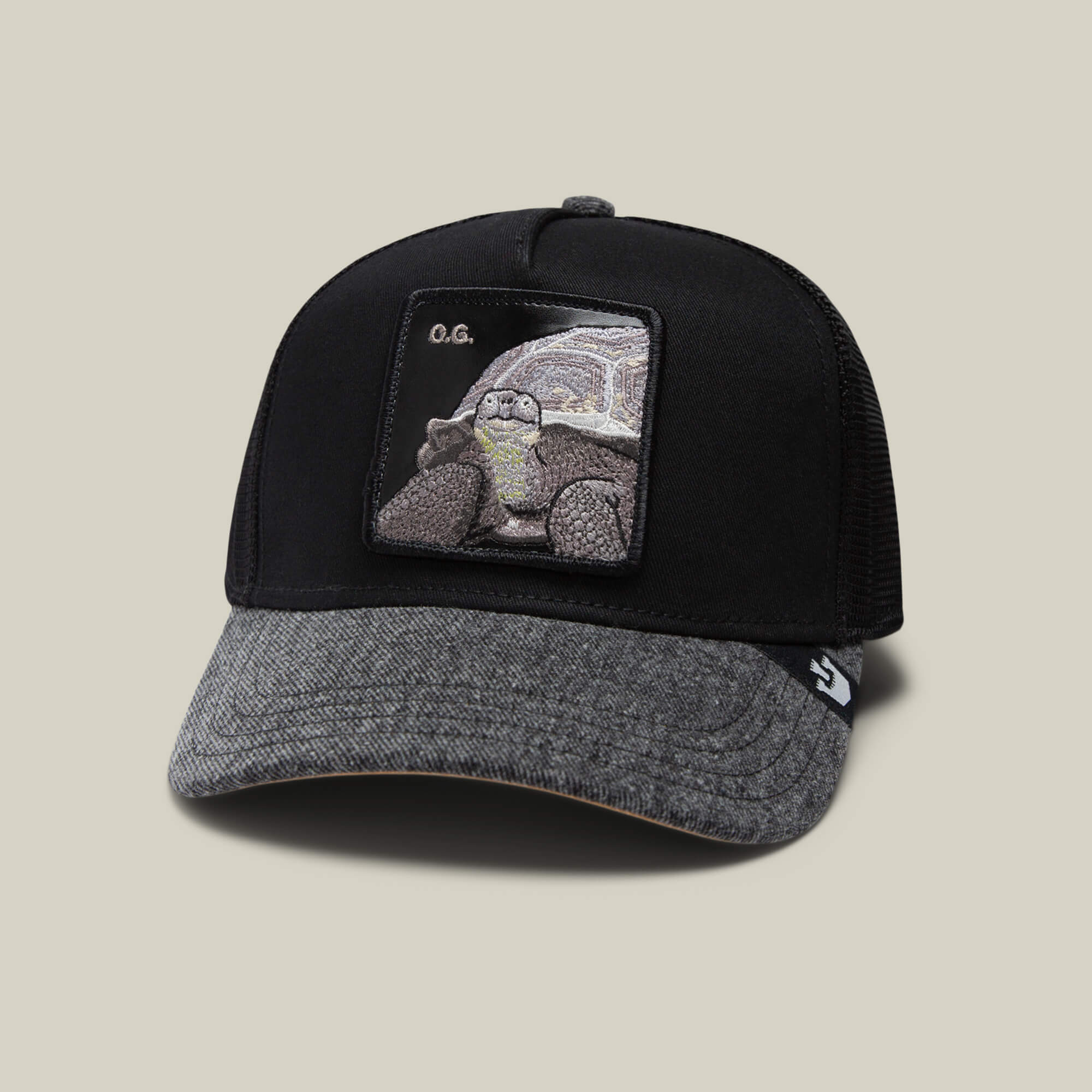 The Farm’s The OG Tortoise is a black and grey denim baseball cap with a front patch featuring an embroidered tortoise and “O.G.” above it.