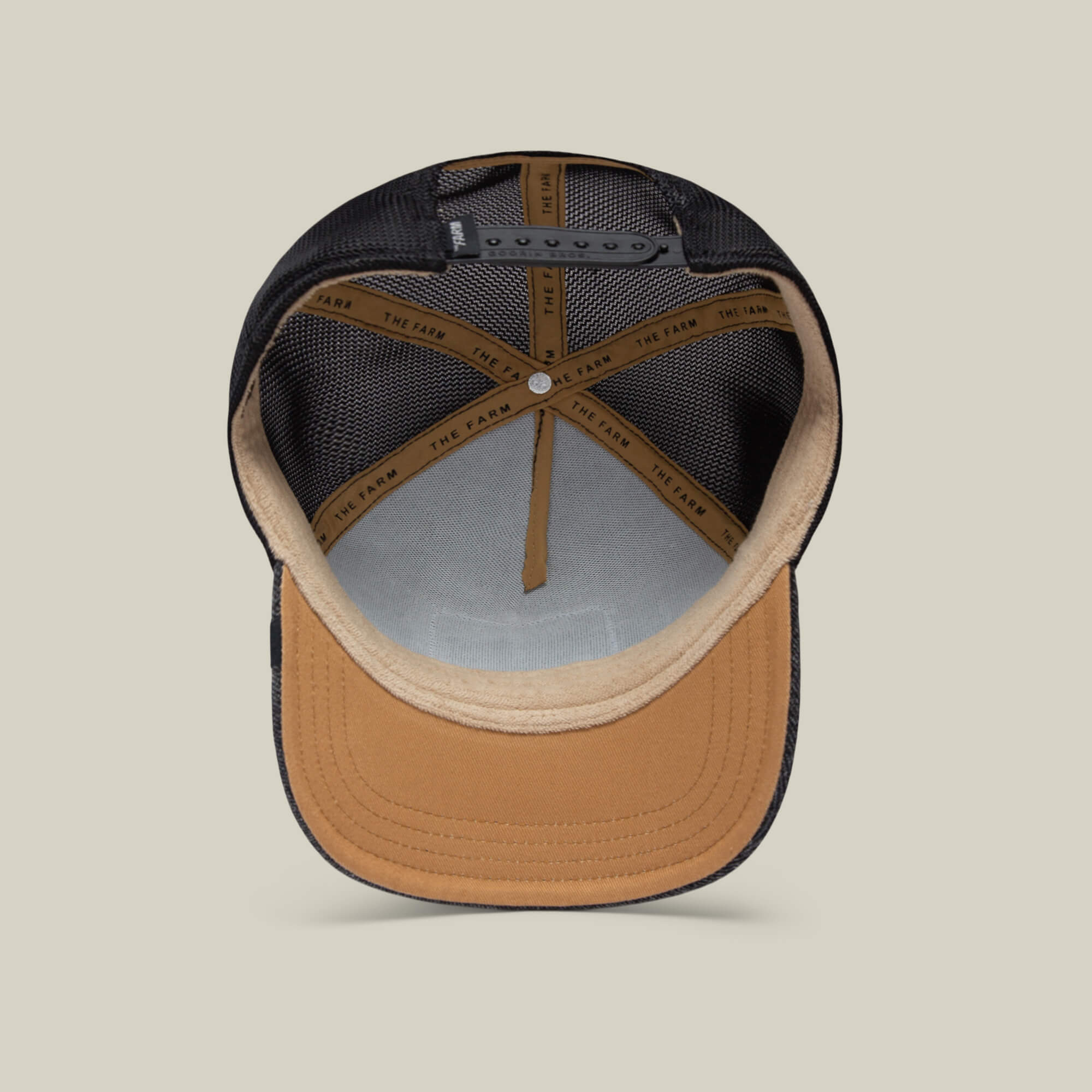 A close-up of The Farm's The OG Tortoise cap in black and tan, featuring mesh panels, adjustable strap, visible inner lining, detailed stitching, and durable denim-inspired craftsmanship.