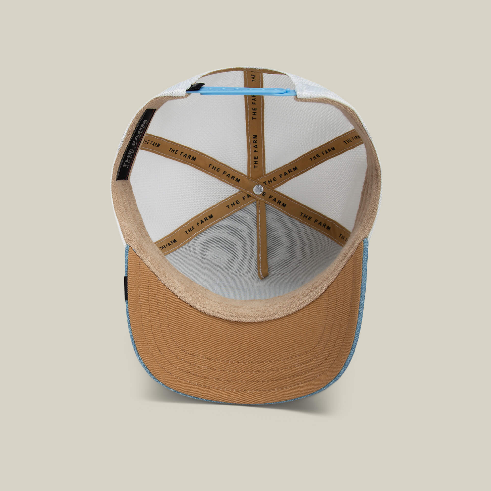 A look inside the Rooster Fan Institution Ball Club cap by Goorin Bros., featuring tan and light blue panels, mesh, detailed stitching, and THE FARM branding—the perfect game-day accessory.