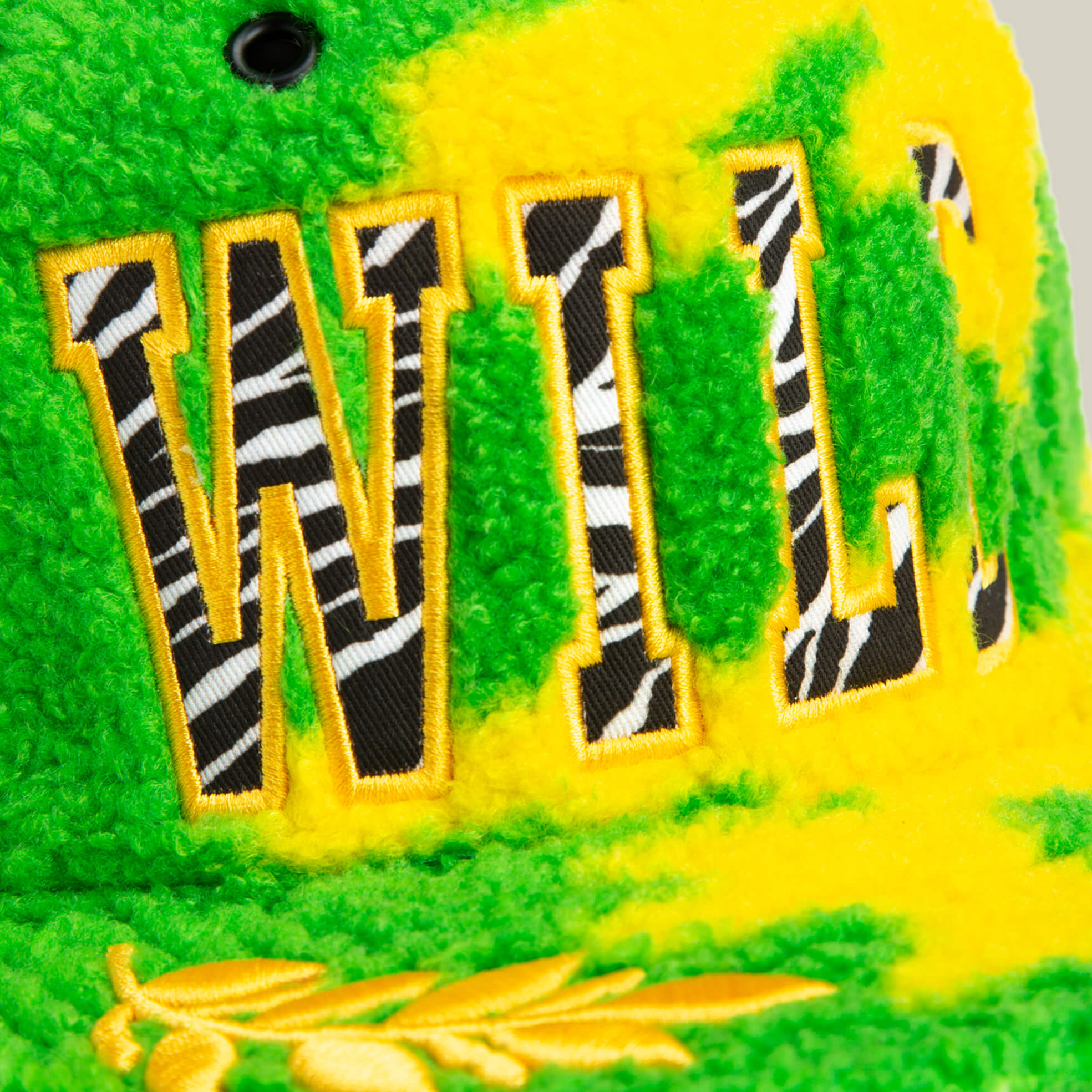 A close-up of the Goorin Bros. Loose Cannon cap featuring neon green and yellow Sherpa fabric, large "WILL" in zebra print jungle lettering, and yellow outline embroidery.