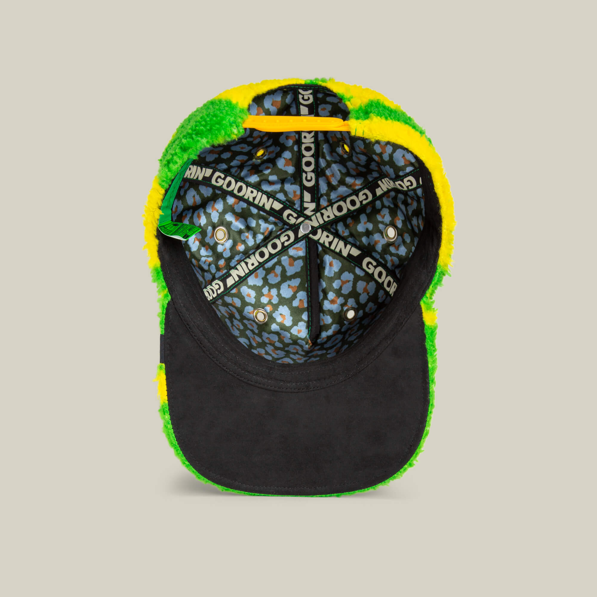 The inside view of the Goorin Bros. Loose Cannon cap features neon green sherpa lining, jungle lettering accents, and black elastic bands with Godring branding, showcased in a bold green, yellow, and black color scheme.