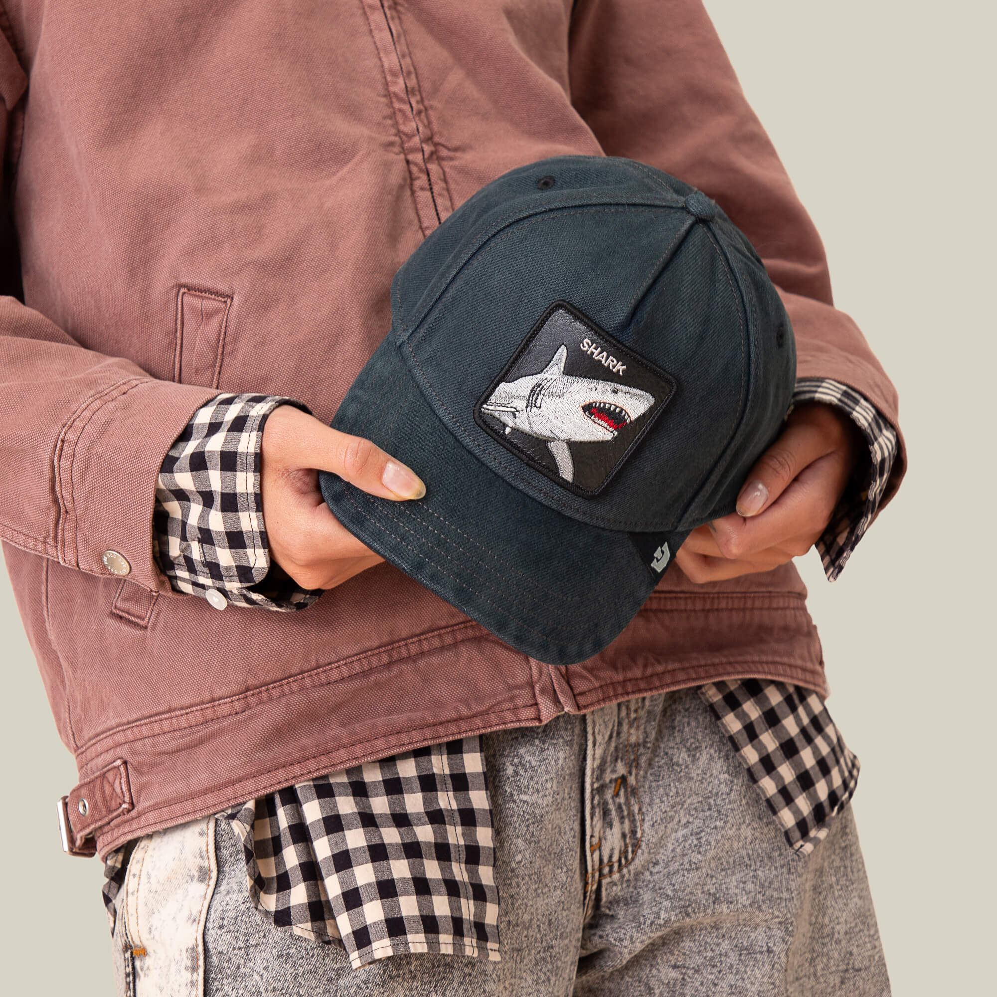 A person holding the Smurf cap by Goorin Bros., its jagged grin patch bringing extra attitude to their style.