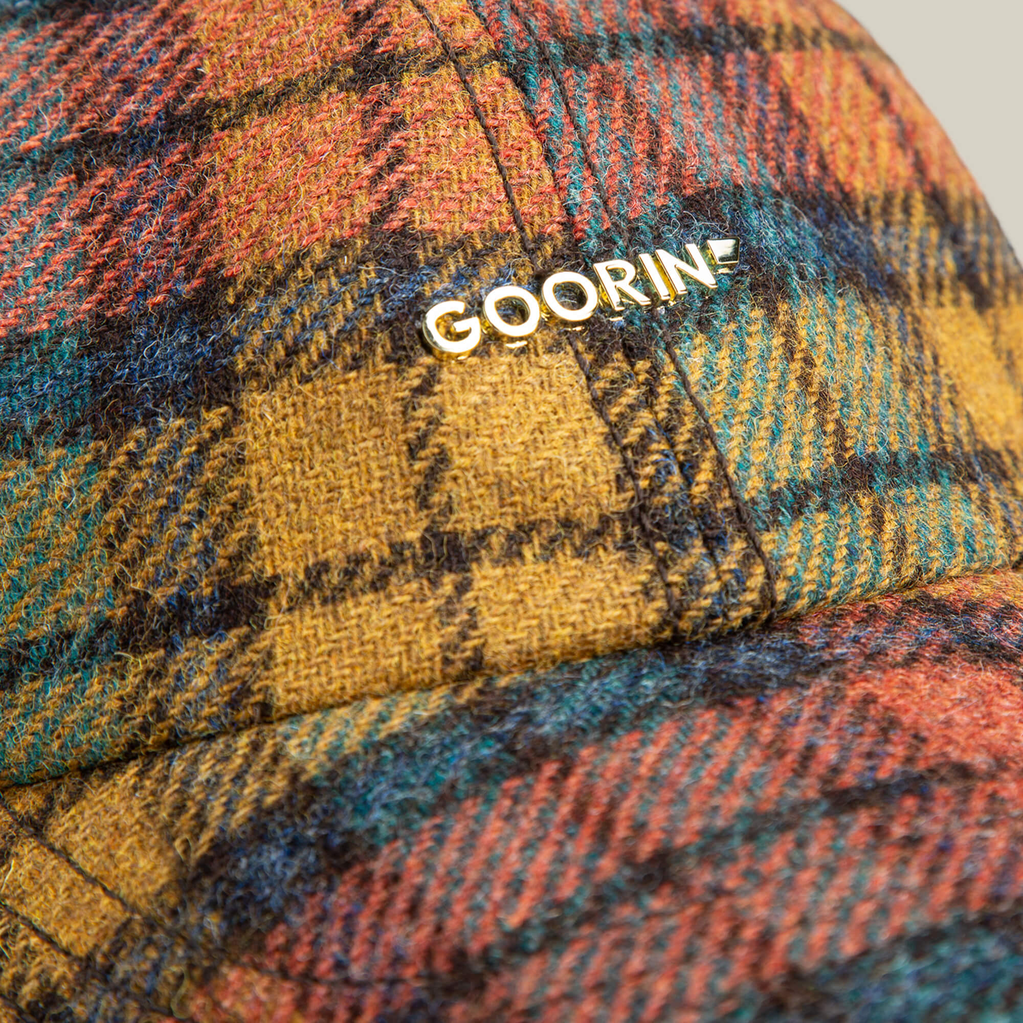Close-up of the Bespoke Wordmark cap by Goorin Bros., featuring a multicolored plaid wool blend and "GOORIN" in white lettering on the front.
