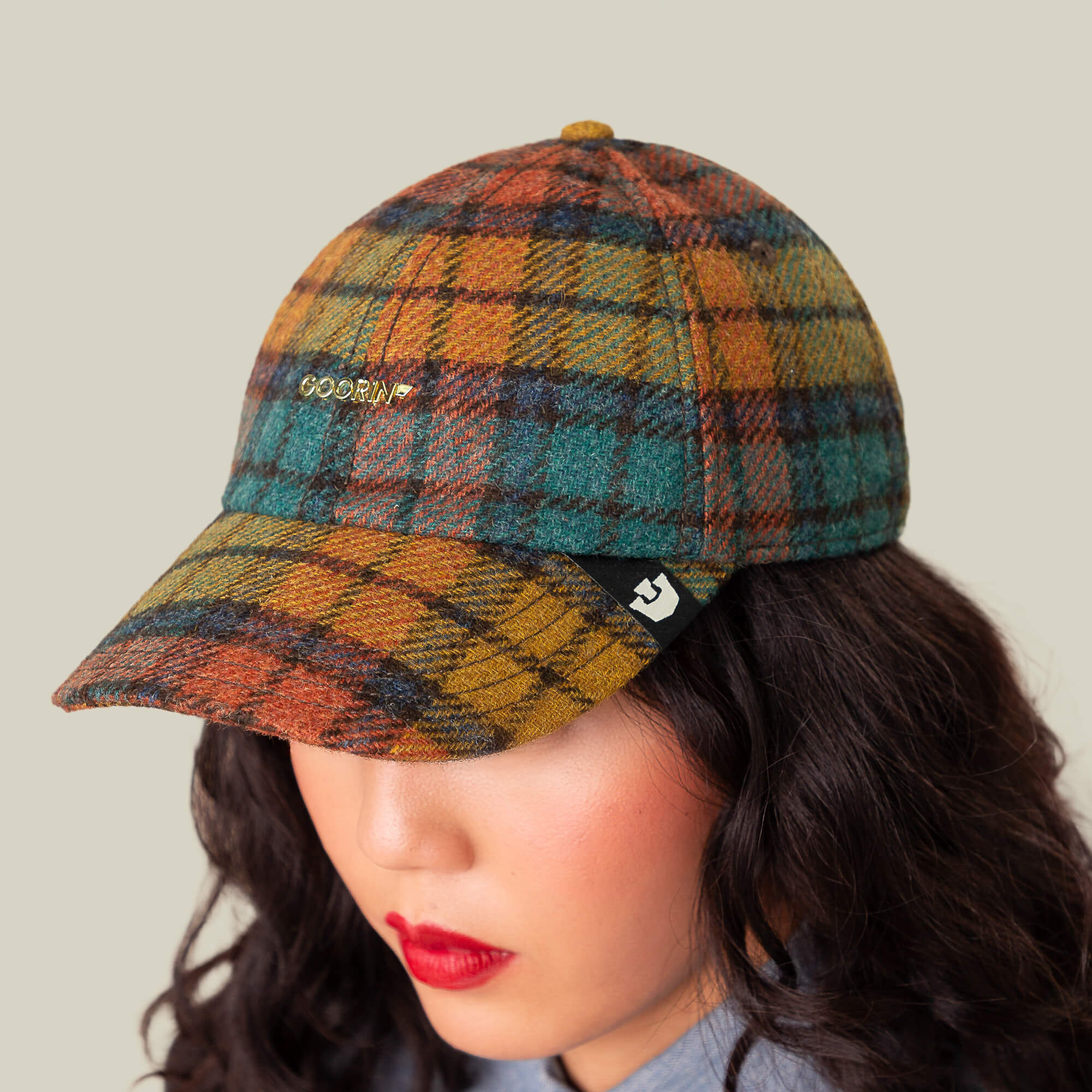 A person wears the Bespoke Wordmark multicolored plaid wool-blend baseball cap by Goorin Bros., featuring an embroidered wordmark on the front, shown from a high angle against a neutral background.