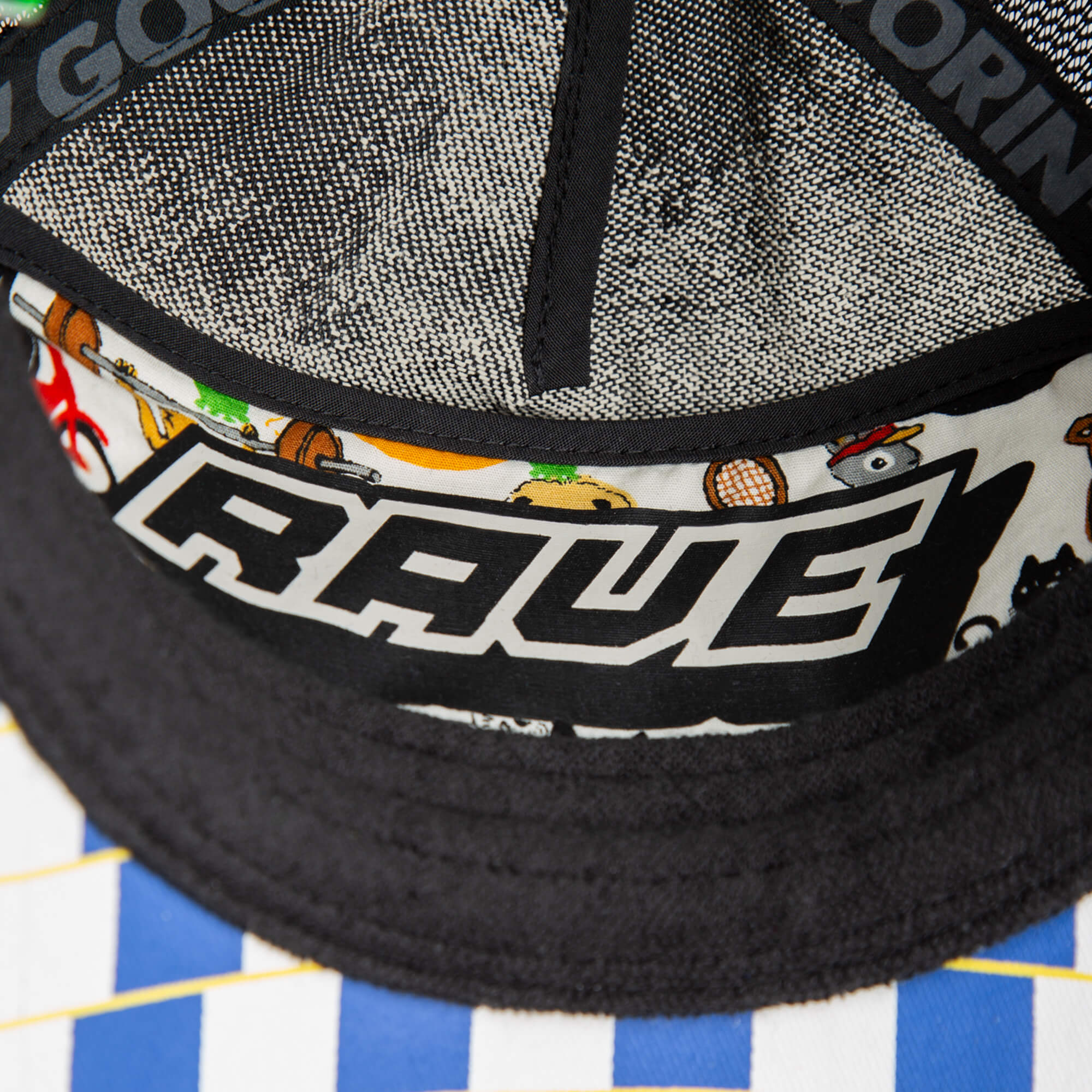 Close-up of the Goorin Bros. Techno rave hat featuring a black brim, patterned white and blue exterior, and "RAVE" printed on the inner lining with colorful graphics—an ideal accessory for festival style.