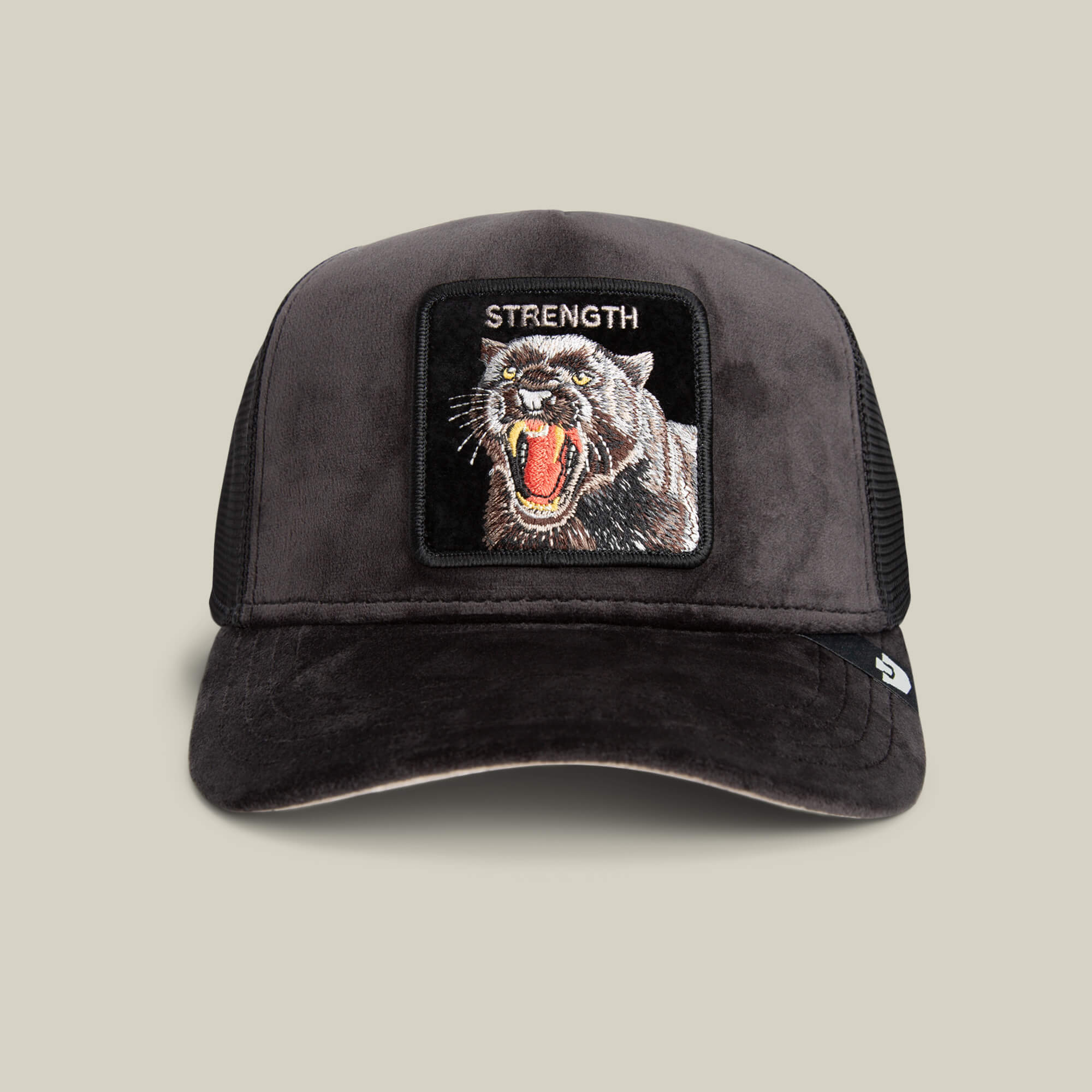 The Goorin Bros. Velour Panther hat in VOID features a black velour finish and a patch with a roaring panther and "STRENGTH" embroidered above, showcased against a beige background.