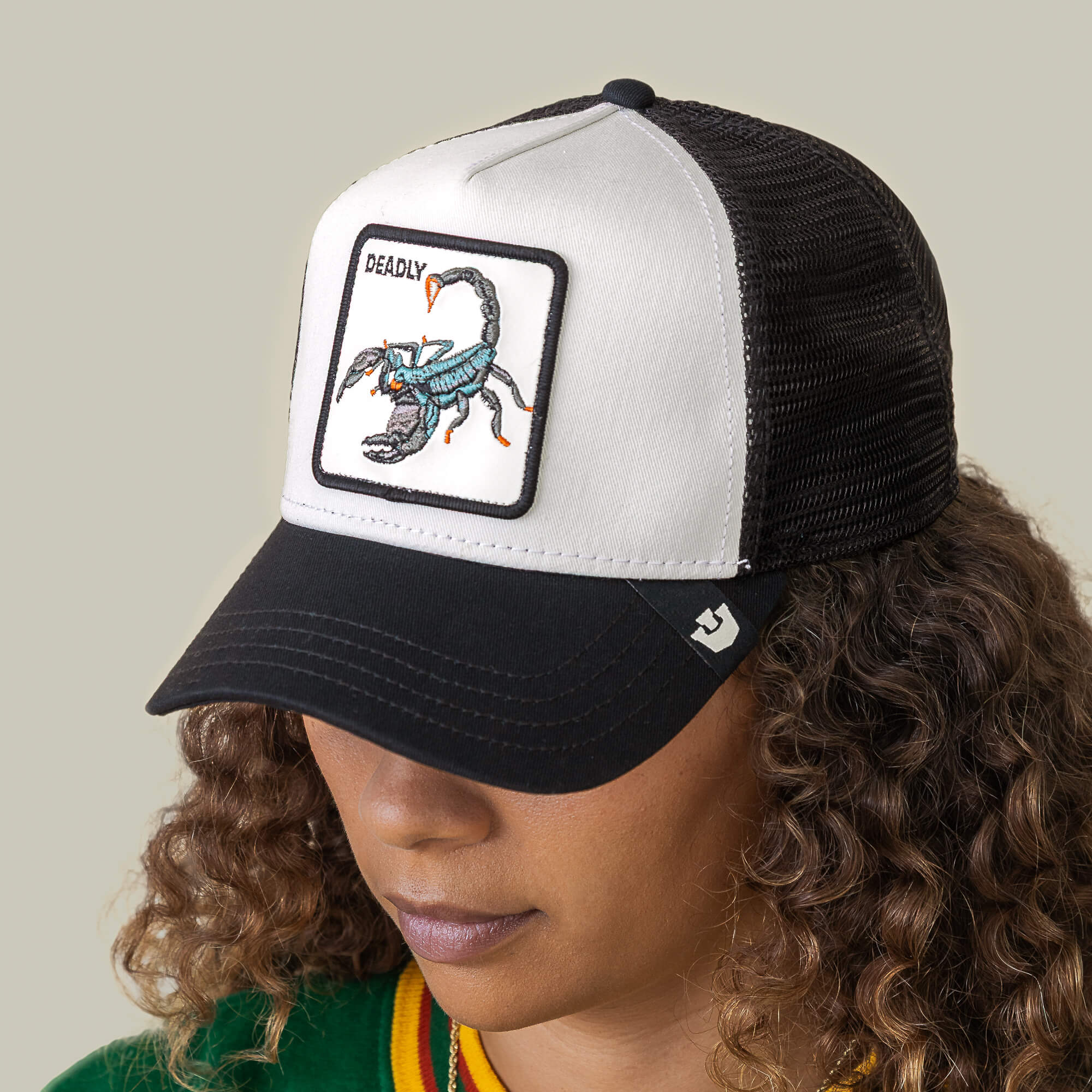 A person wearing the Goorin Bros. "Deadly" black and white mesh hat with a patch featuring an embroidered scorpion.