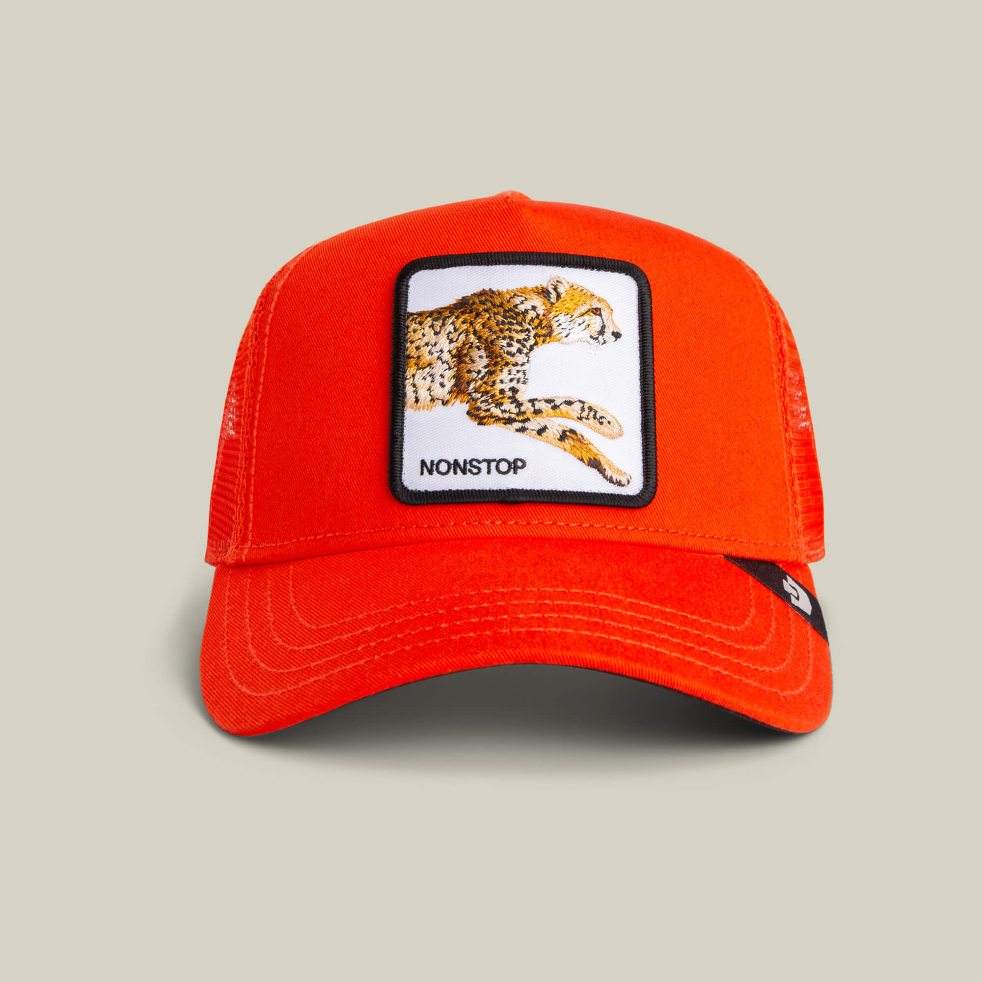 The Nonstop Cheetah by Goorin Bros. is a vibrant orange mesh trucker cap with a rectangular patch featuring a cheetah illustration and "NONSTOP" on the front, embodying speed and style.