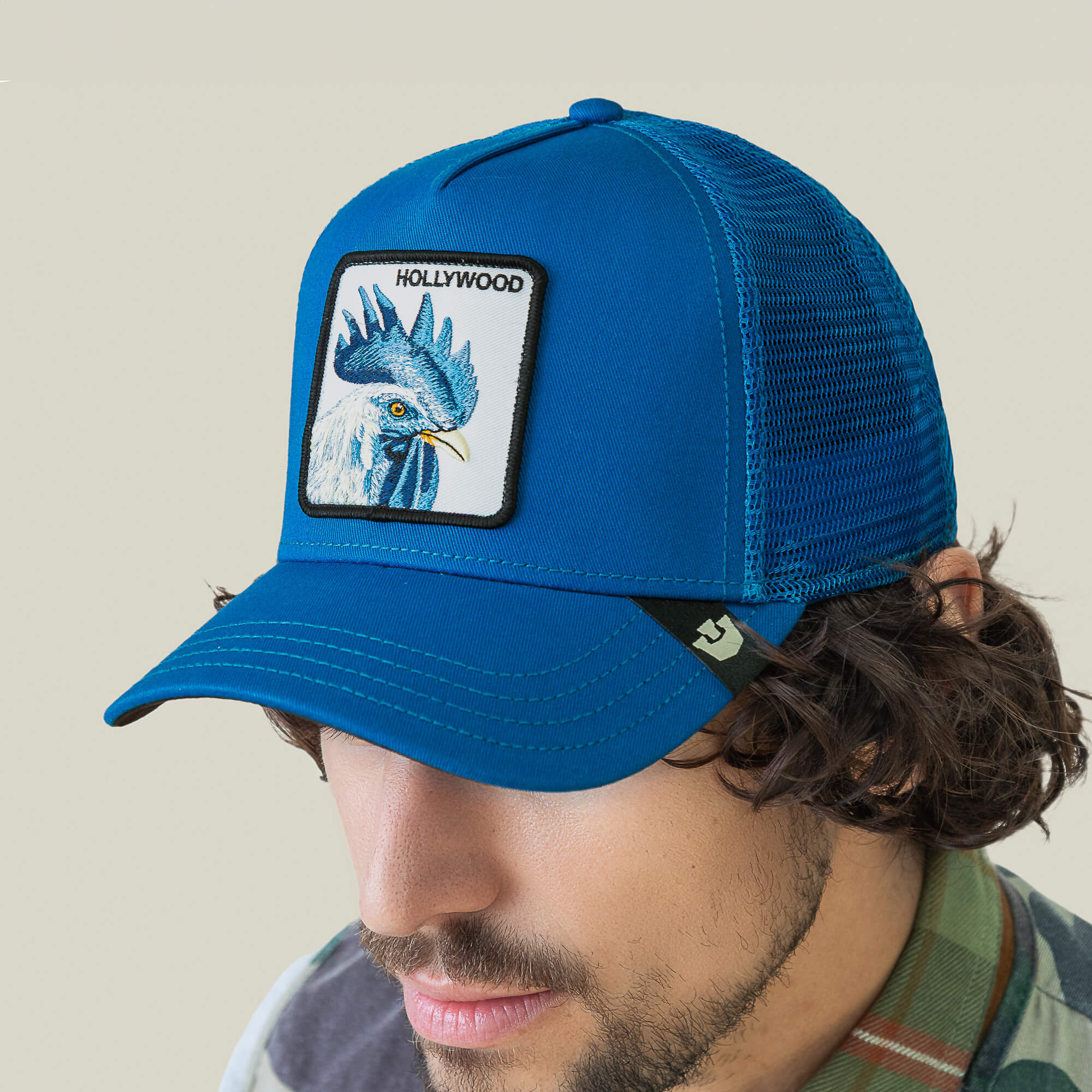 A man wearing the Goorin Bros. Hollywood Rooster cap, a blue mesh baseball hat with a rooster patch—ideal for strolling the Hills or turning heads on the red carpet.