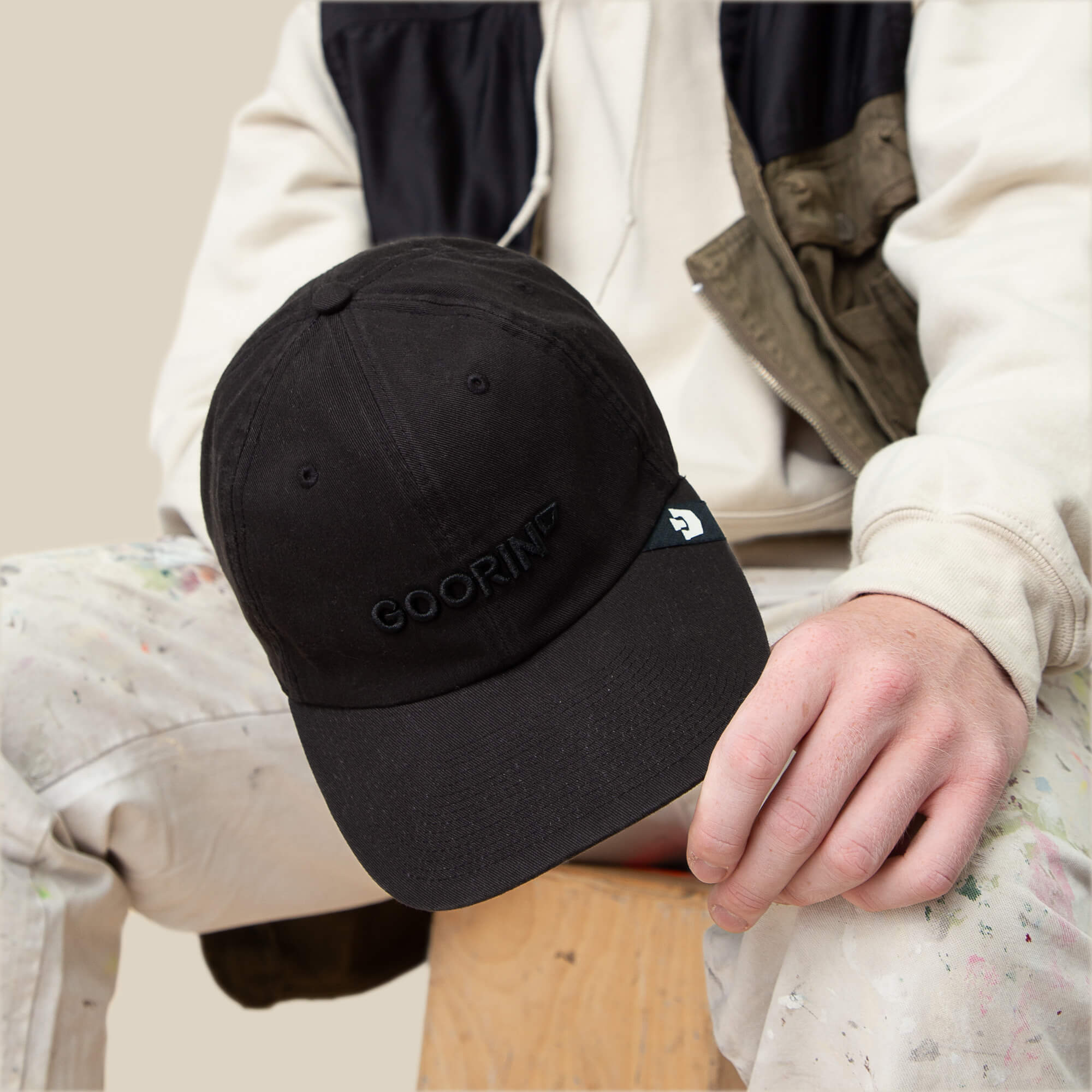 A person wearing the Papa Core black hat by Goorin Bros., featuring a curved brim and a soft crown.