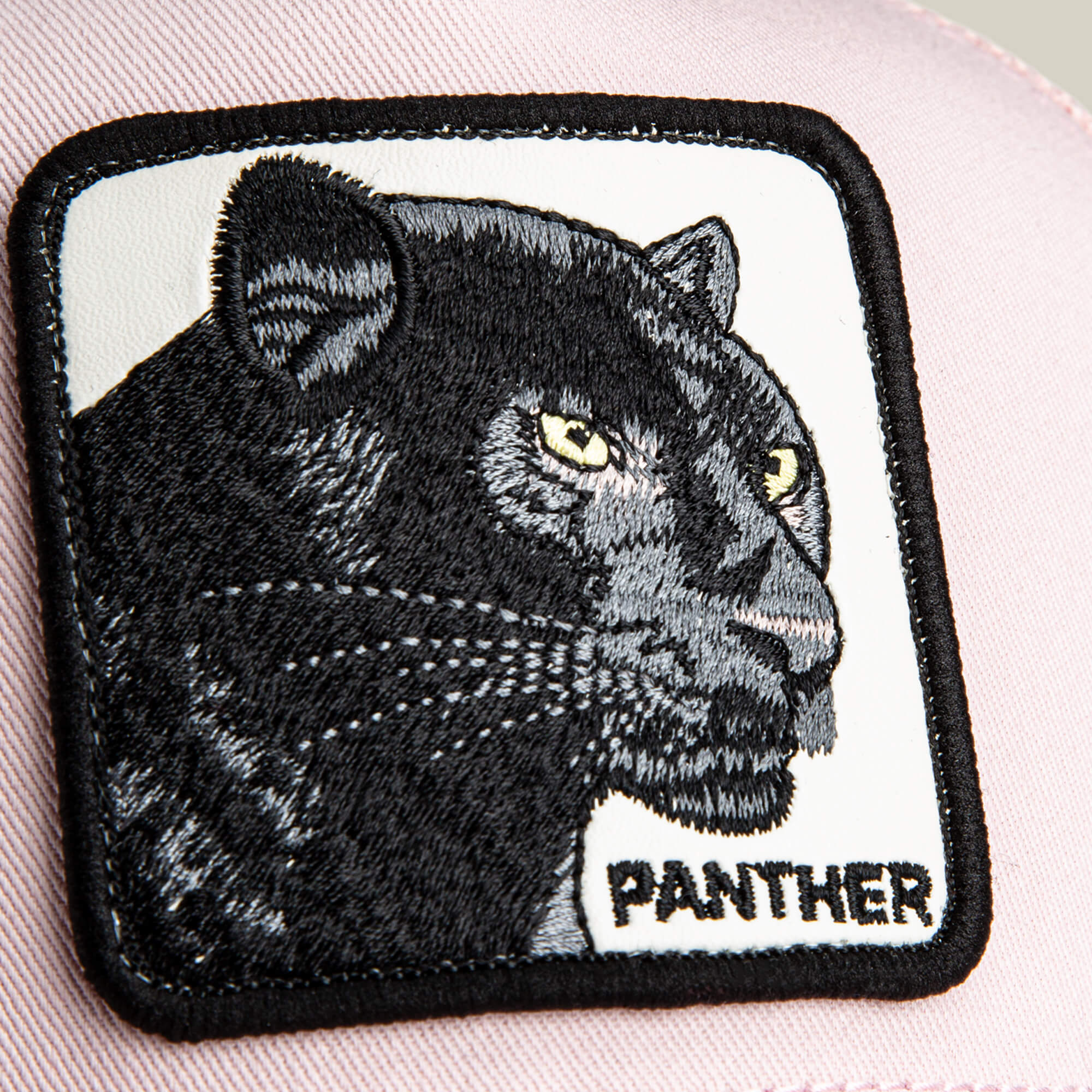 Embroidered patch of a black panther’s head with "PANTHER" on light-colored fabric—ideal to personalize your Goorin Bros. Panther Trucker hat or add a bold touch to any look.