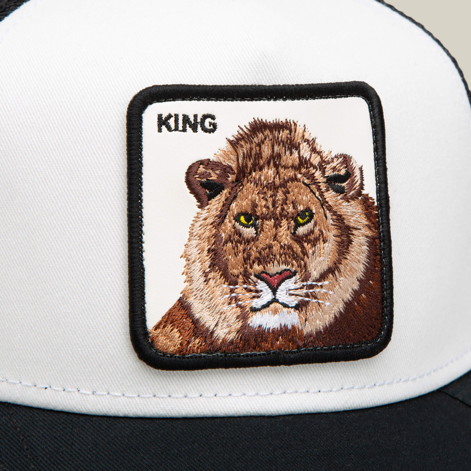 A close-up of the King Trucker hat by Goorin Bros., showcasing an embroidered lion face patch with "KING" stitched above—ideal for making a bold statement.