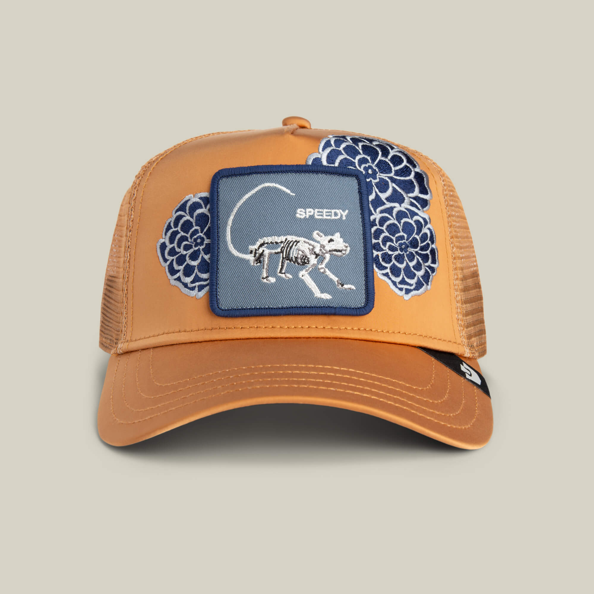 The Dia De Speedy by Goorin Bros. is a HEAT-colored mesh trucker hat featuring a front patch with a rodent skeleton labeled "Speedy," blue floral designs, and "fearless" embroidery on the crown.