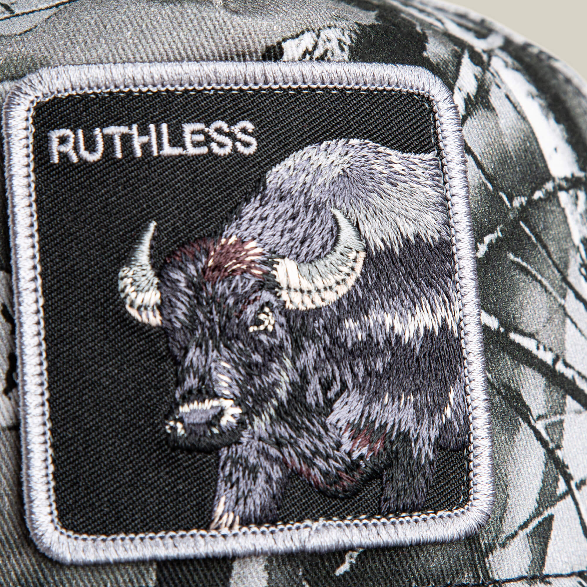 A close-up of a Goorin Bros. Ruthless Camo patch featuring an embroidered buffalo and the word “RUTHLESS” on a camo-patterned background.