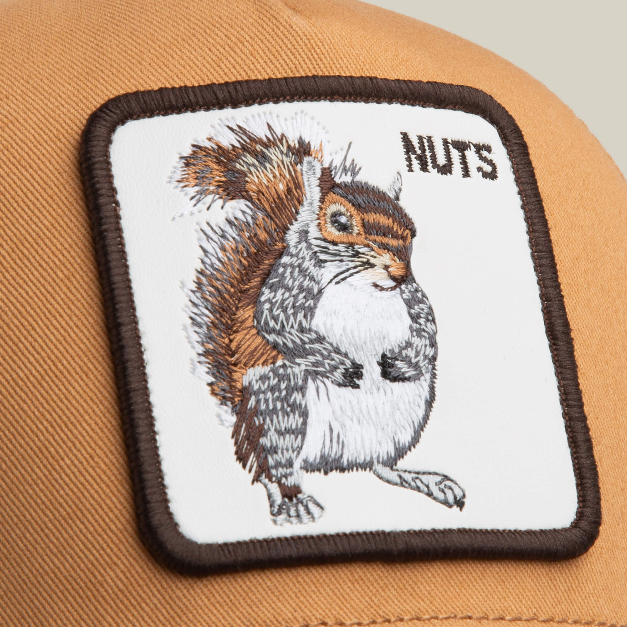 Get a closer look at the Goorin Bros. Nuts Trucker hat—a brown cap with a quirky squirrel patch and NUTS embroidery, perfect for adding playful style to any look.