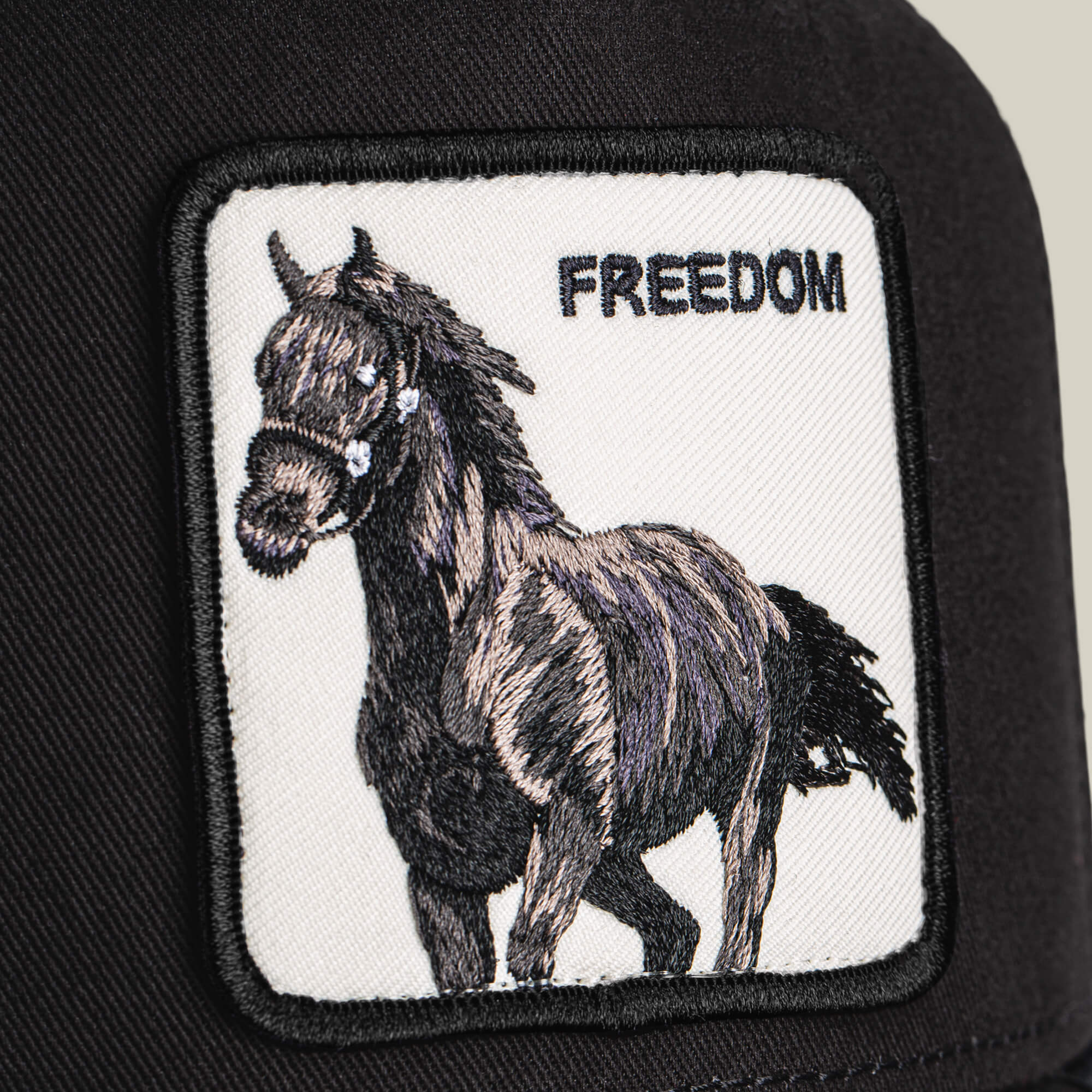 A close-up of the Goorin Bros. Freedom Horse black cap, showcasing a horse trucker patch and bold FREEDOM lettering—an emblem of wild, open-road spirit.