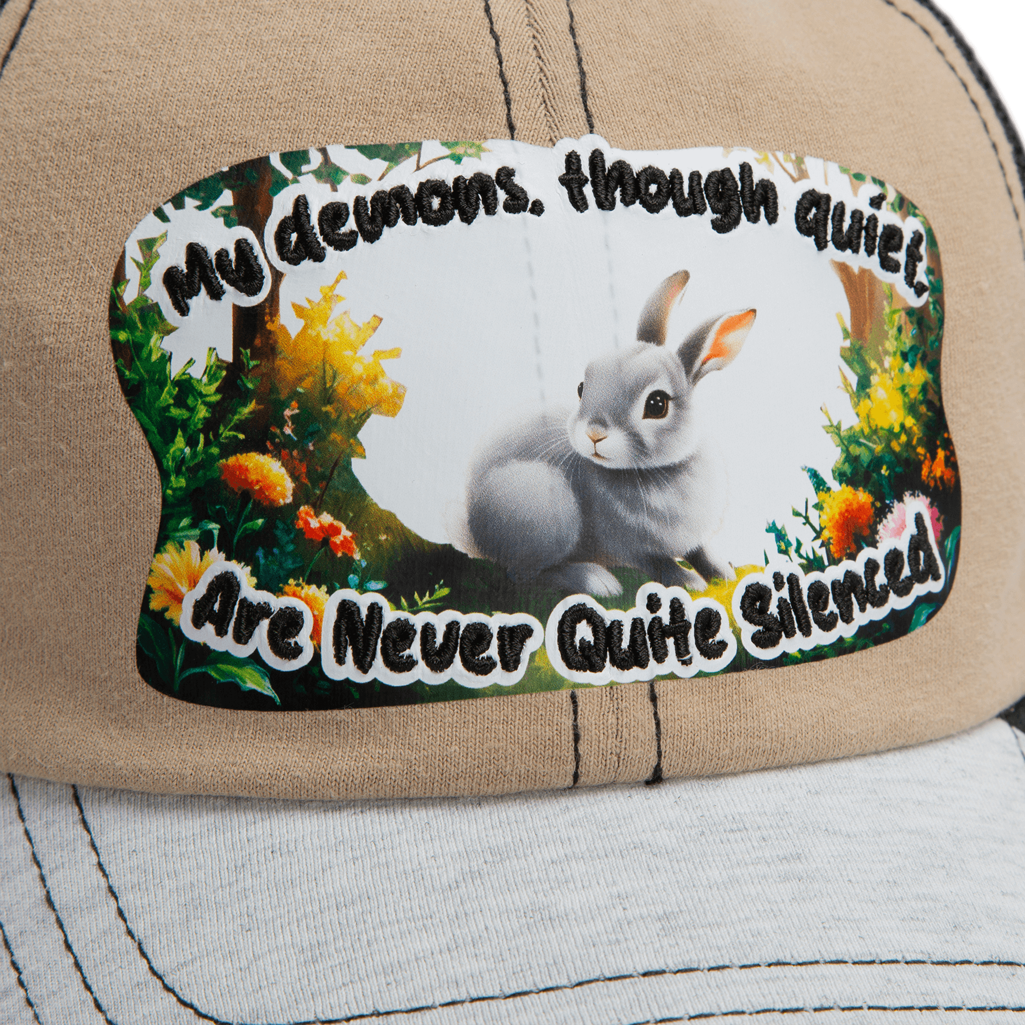 The Goorin Bros. Lil Ronin tan cap from our Storybook collection has white stitching and a patch with a gray rabbit and the words, “My demons, though quiet, are never quite silenced.”.