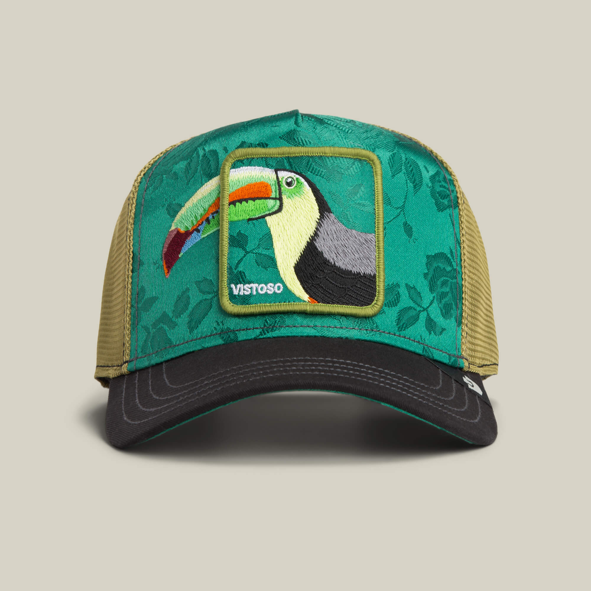 The Goorin Bros. Belize Toucan trucker hat features a green and khaki design with a floral front panel, a Belize Toucan patch, and the word "VISTOSO.