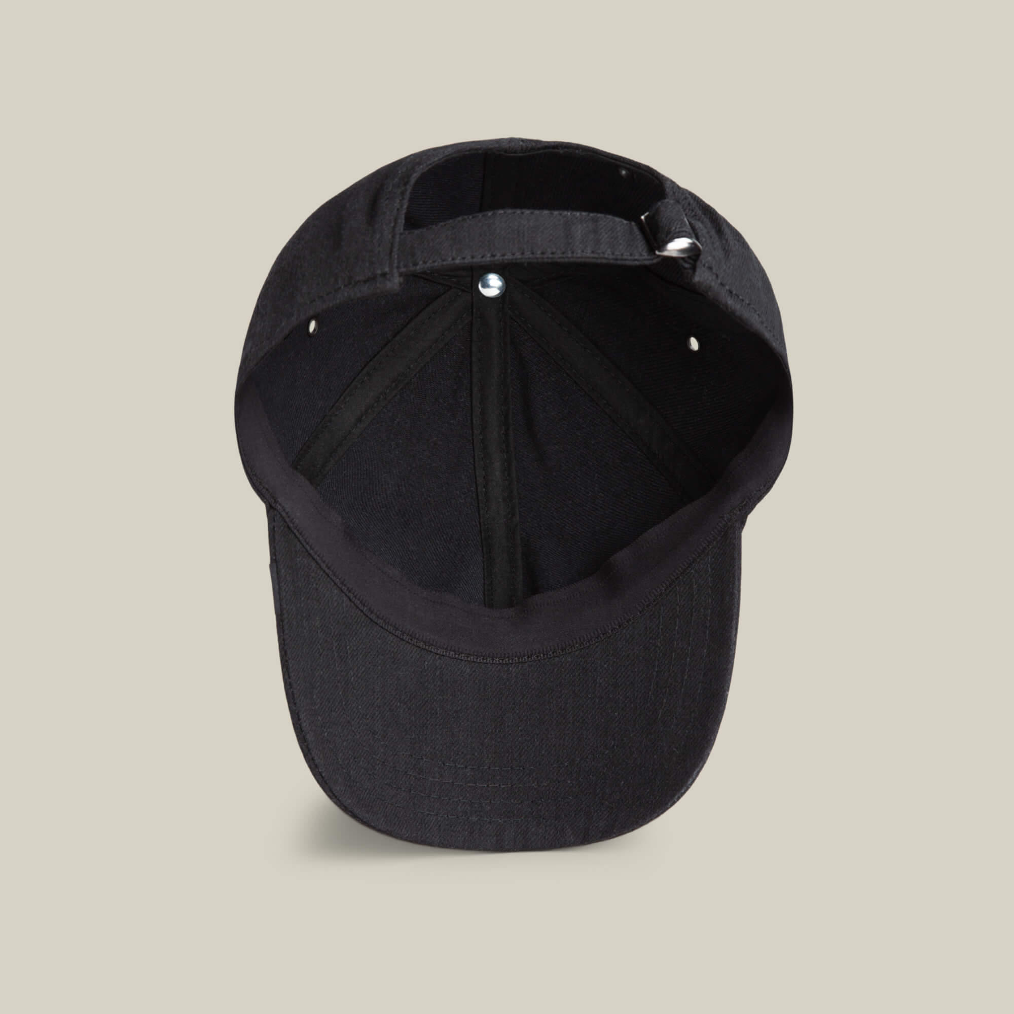 A view of the underside of the Goorin Bros. Clean Denim Papa dad cap, displaying its inner seams, sweatband, and adjustable strap on a plain beige background.