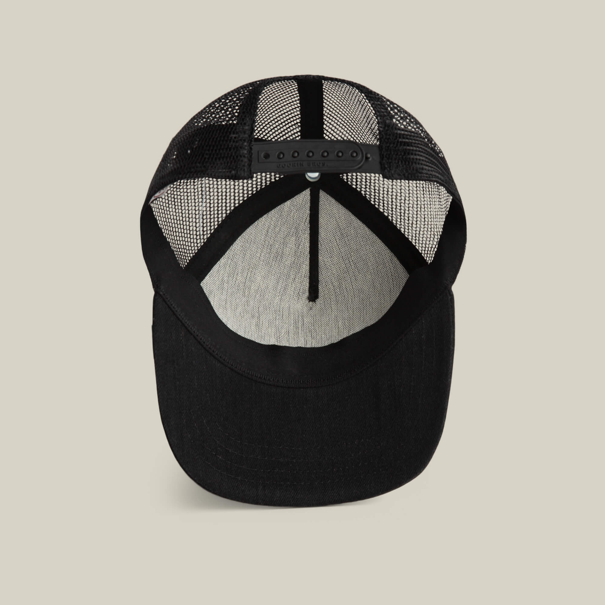 The Goorin Bros. Clean Denim Trucker is a black mesh hat shown from underneath, highlighting its adjustable snapback closure and gray inner lining—designed in the classic denim trucker style.
