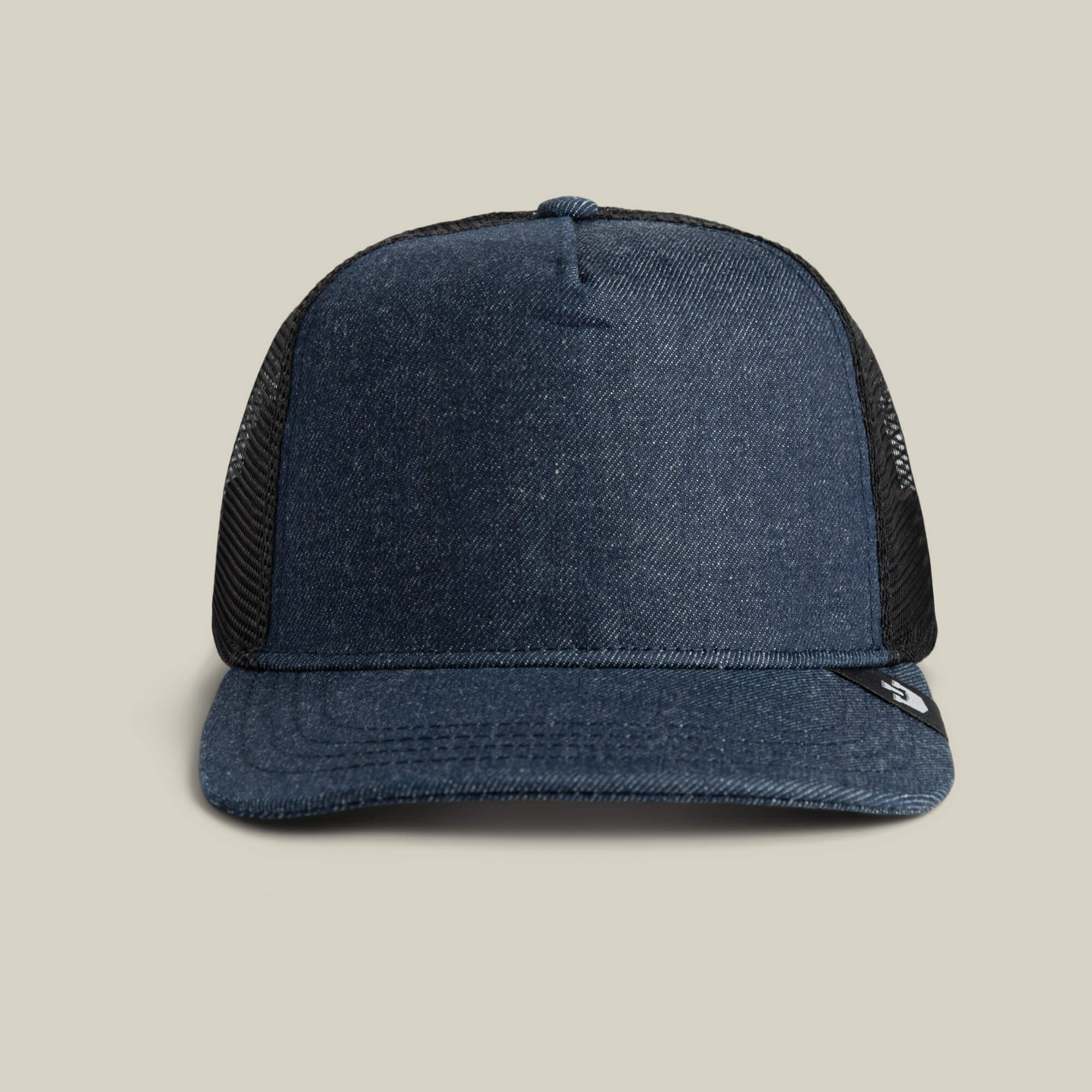 The Clean Denim Trucker by Goorin Bros. features a curved brim and black mesh back, crafted in the USA and shown on a beige background.