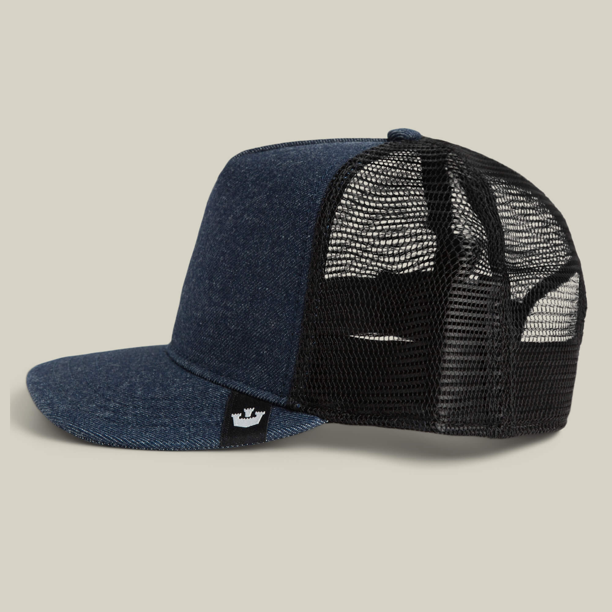The Goorin Bros. Clean Denim Trucker cap features blue denim, a black mesh back, flat brim, and a side black tag with a white crown logo. Made in the USA and shown on a neutral background.