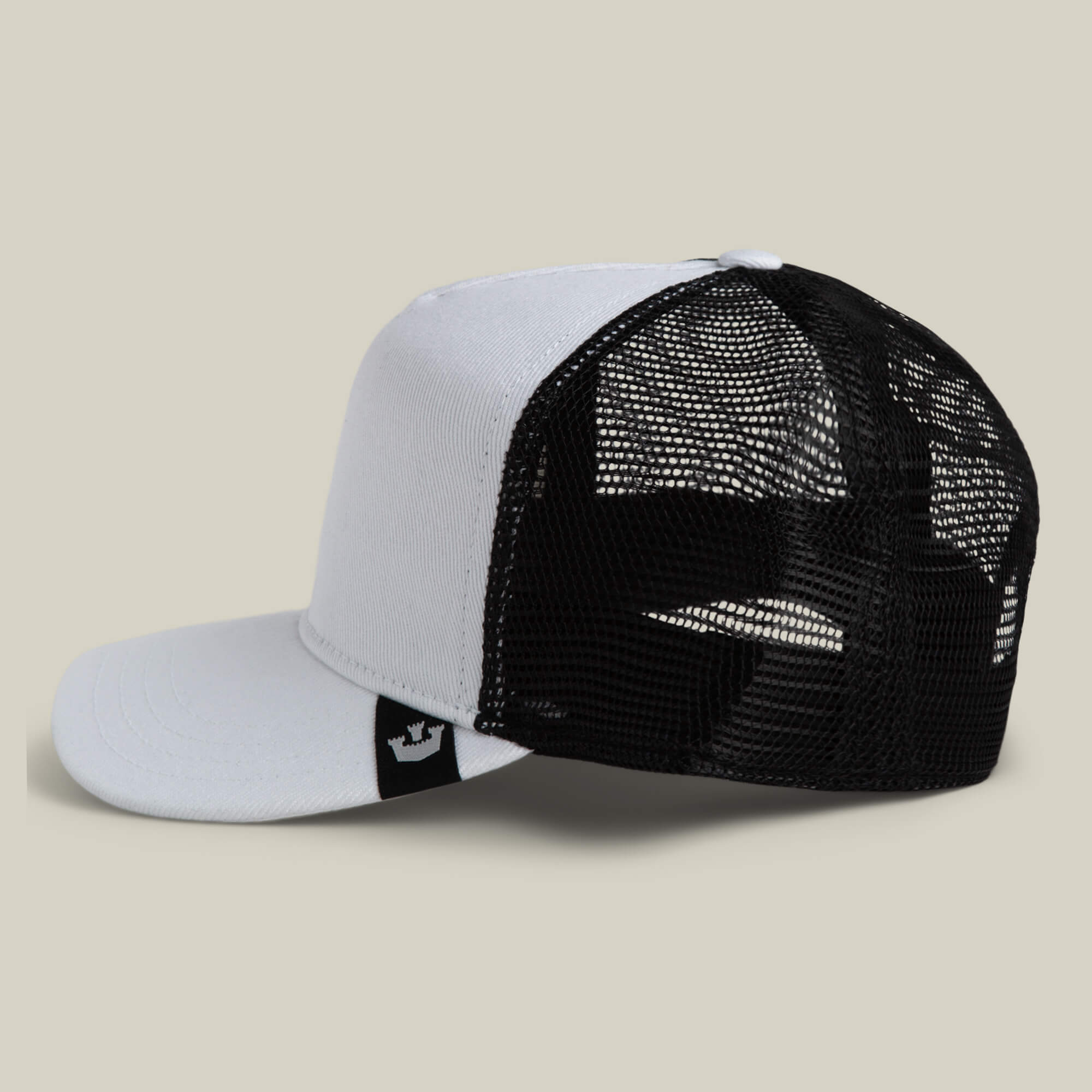 The Goorin Bros. Clean Denim Trucker cap, white and black mesh, made in the USA, is displayed on a beige background with its bill facing left and the back mesh in clear view.