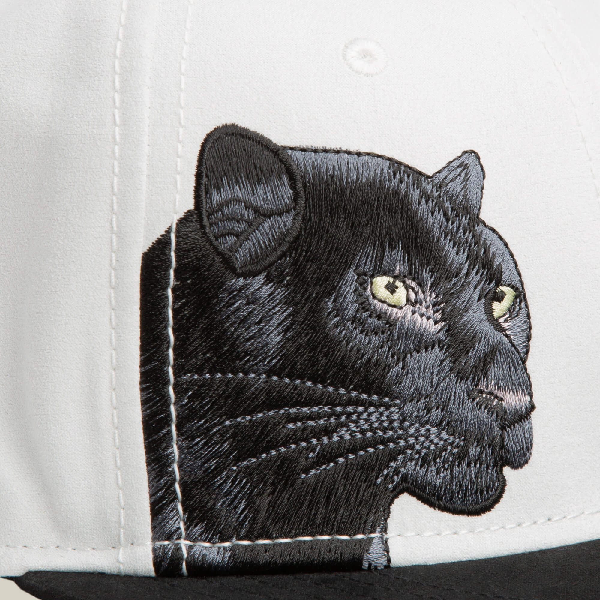 Close-up of the Goorin Bros. 6-Panel Panther Script snapback, a white and black hat with an embroidered black panther head with yellow eyes on the front panel.