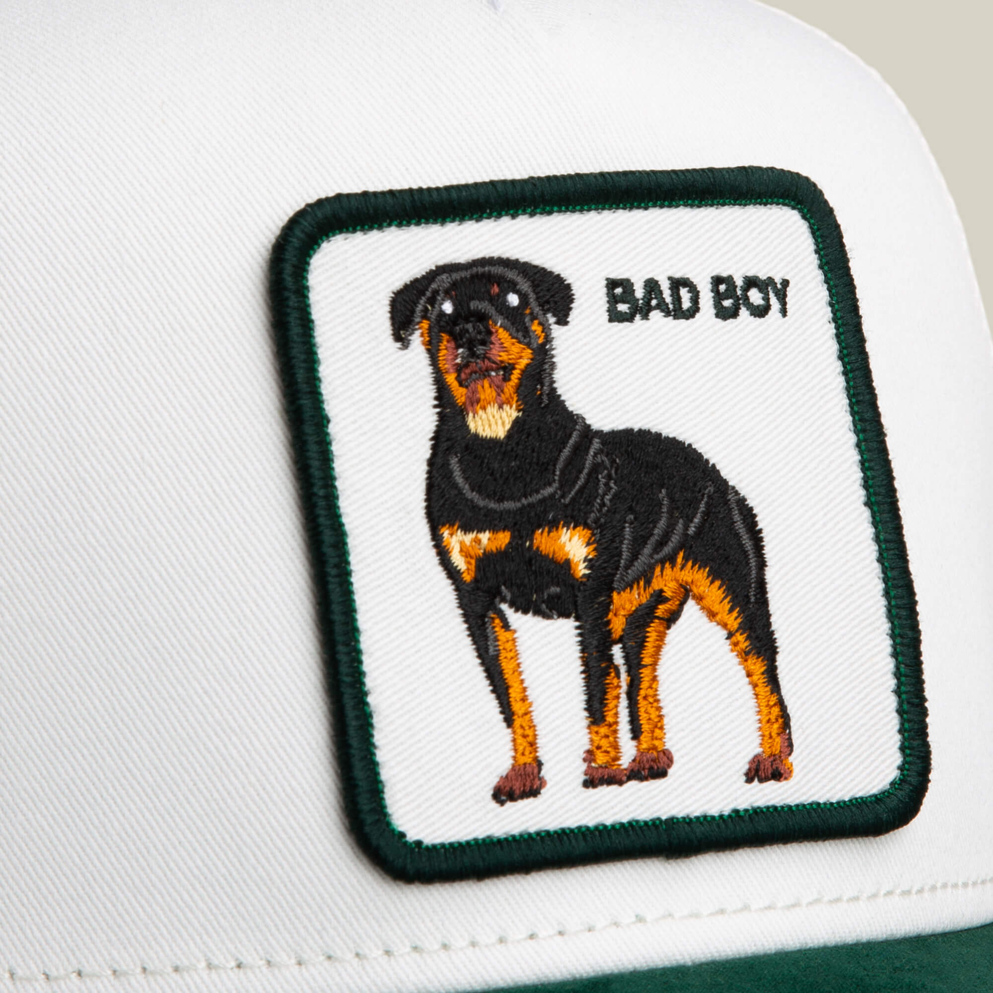 A close-up of the Goorin Bros. Suede Bad Boy cap, showcasing a bold embroidered Rottweiler "BAD BOY" patch for a striking dog-inspired design.