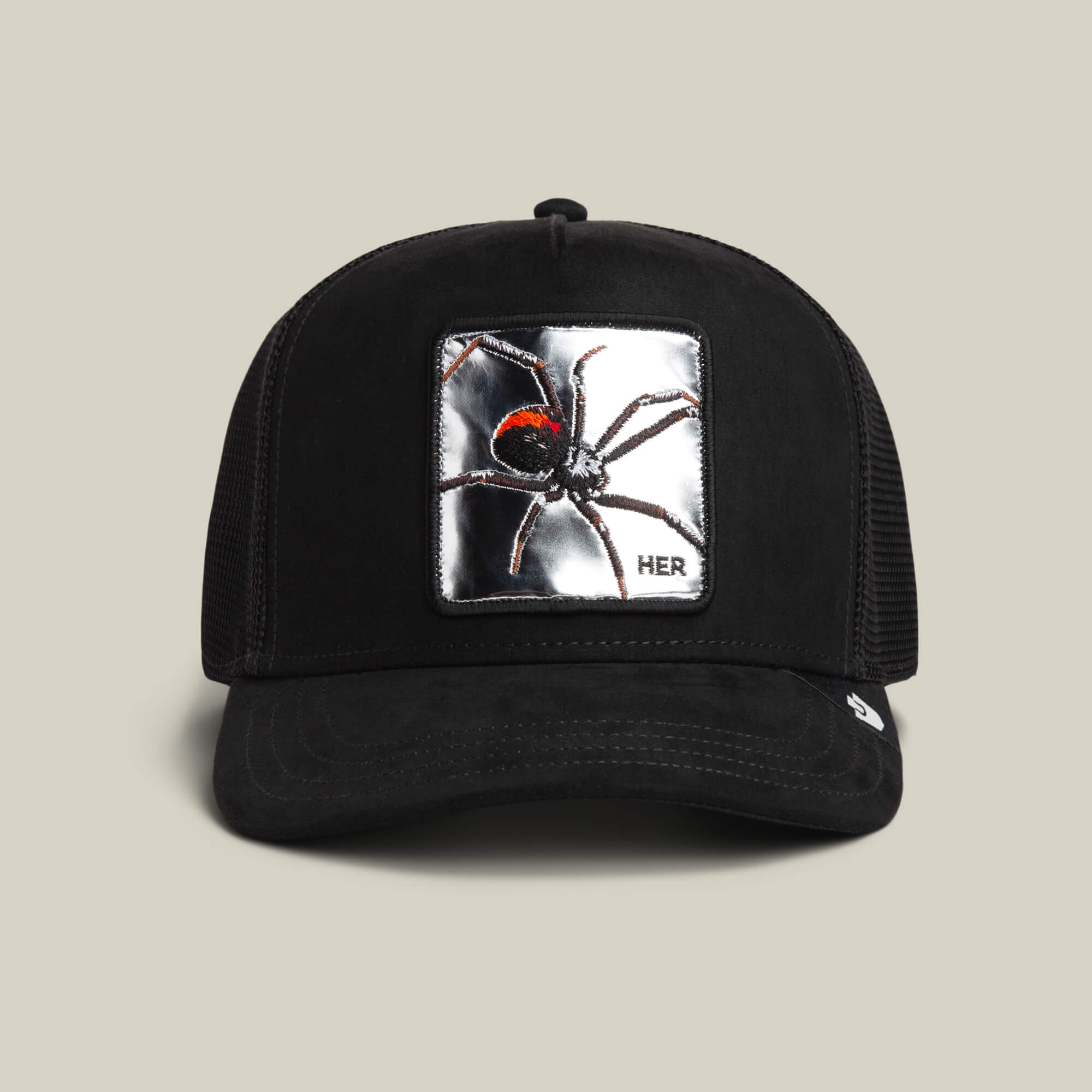 The Goorin Bros. Silver Spider VOID trucker hat features a mesh back and a metallic silver spider patch with "HER" in the corner.