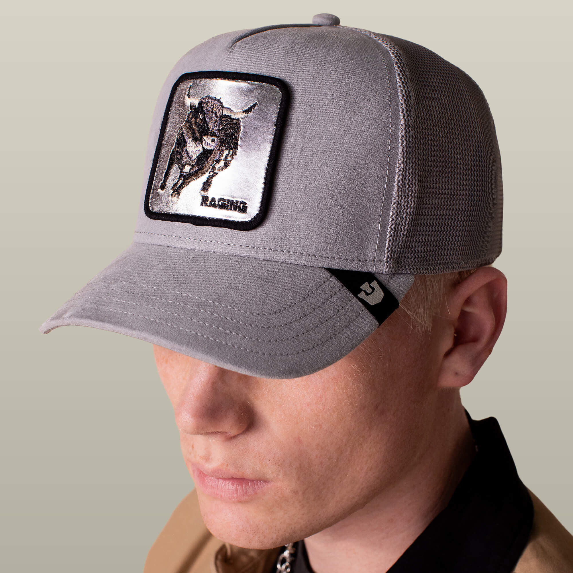 A person wearing the Goorin Bros. Silver Bull gray trucker cap with a mesh back and a front bull patch that says RAGING.