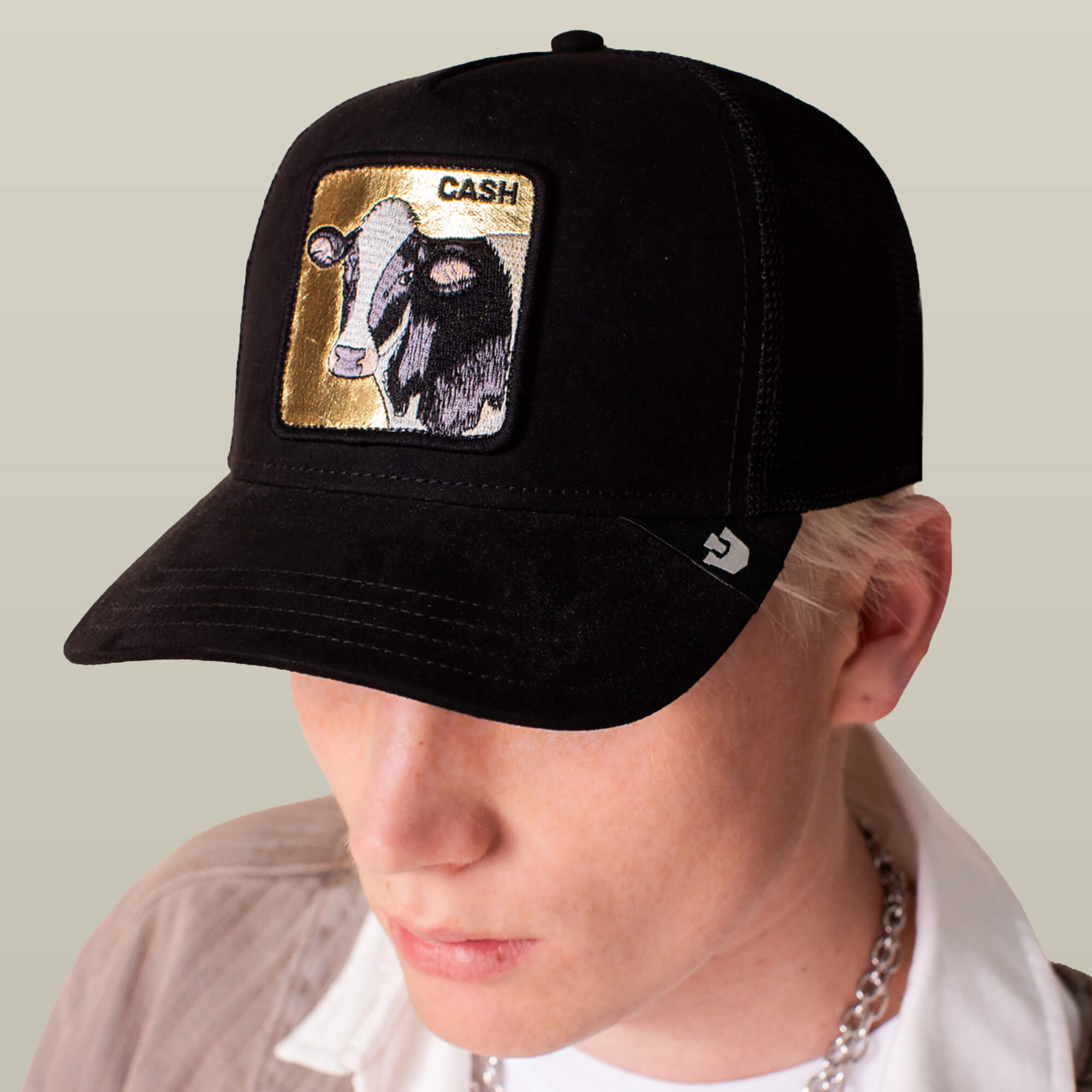 A person wearing the Goorin Bros. Golden Cow black suede cap, featuring an embroidered gold-backed cow patch and "CASH" on the front panel.