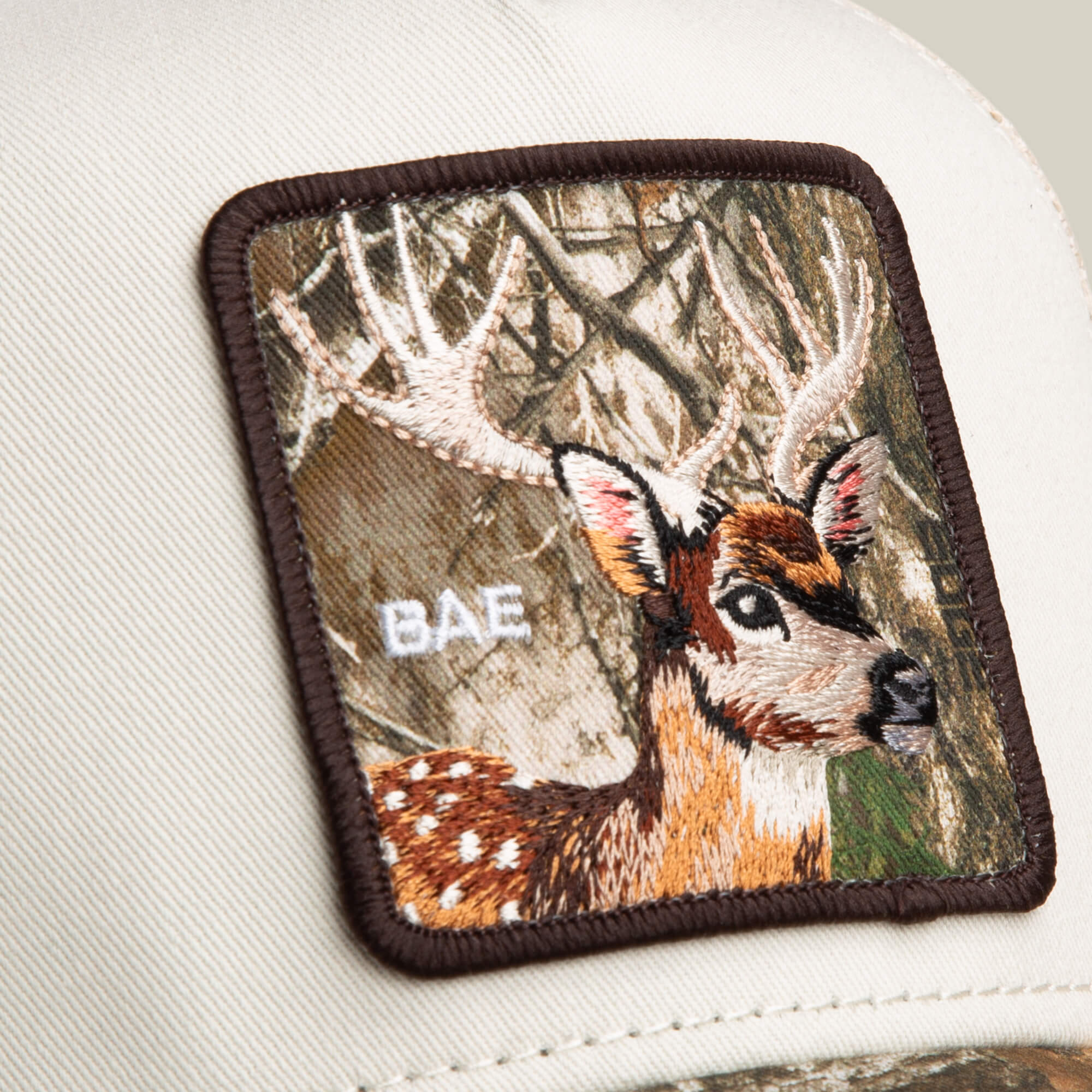 Close-up of the Goorin Bros. Realtree Edge Bae Doe hat, showcasing a camo colorway and a rectangular patch with an embroidered deer, antlers, and "BAE.