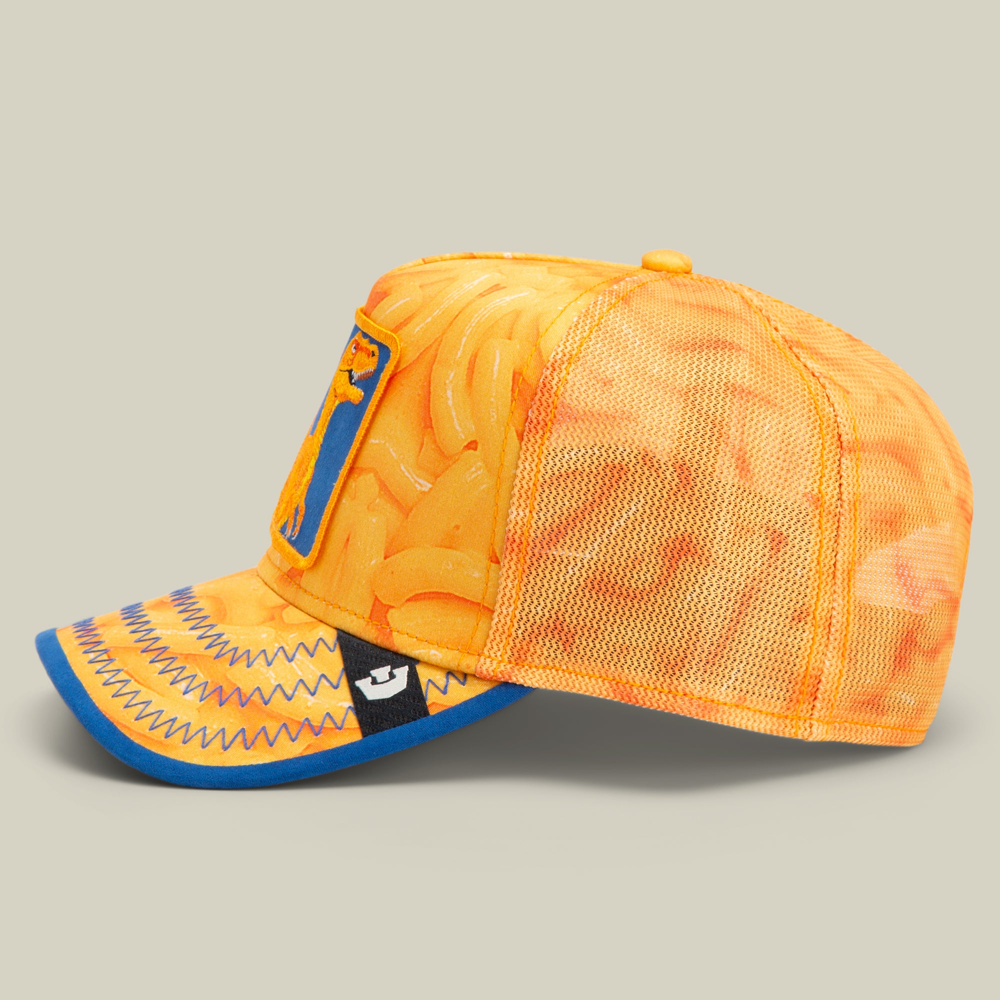 Orange mesh baseball cap with a macaroni and cheese pattern and blue zigzag stitching along the visor, shown on a plain beige background. Designed by Goorin, known for American made quality beyond their iconic fedora hats.