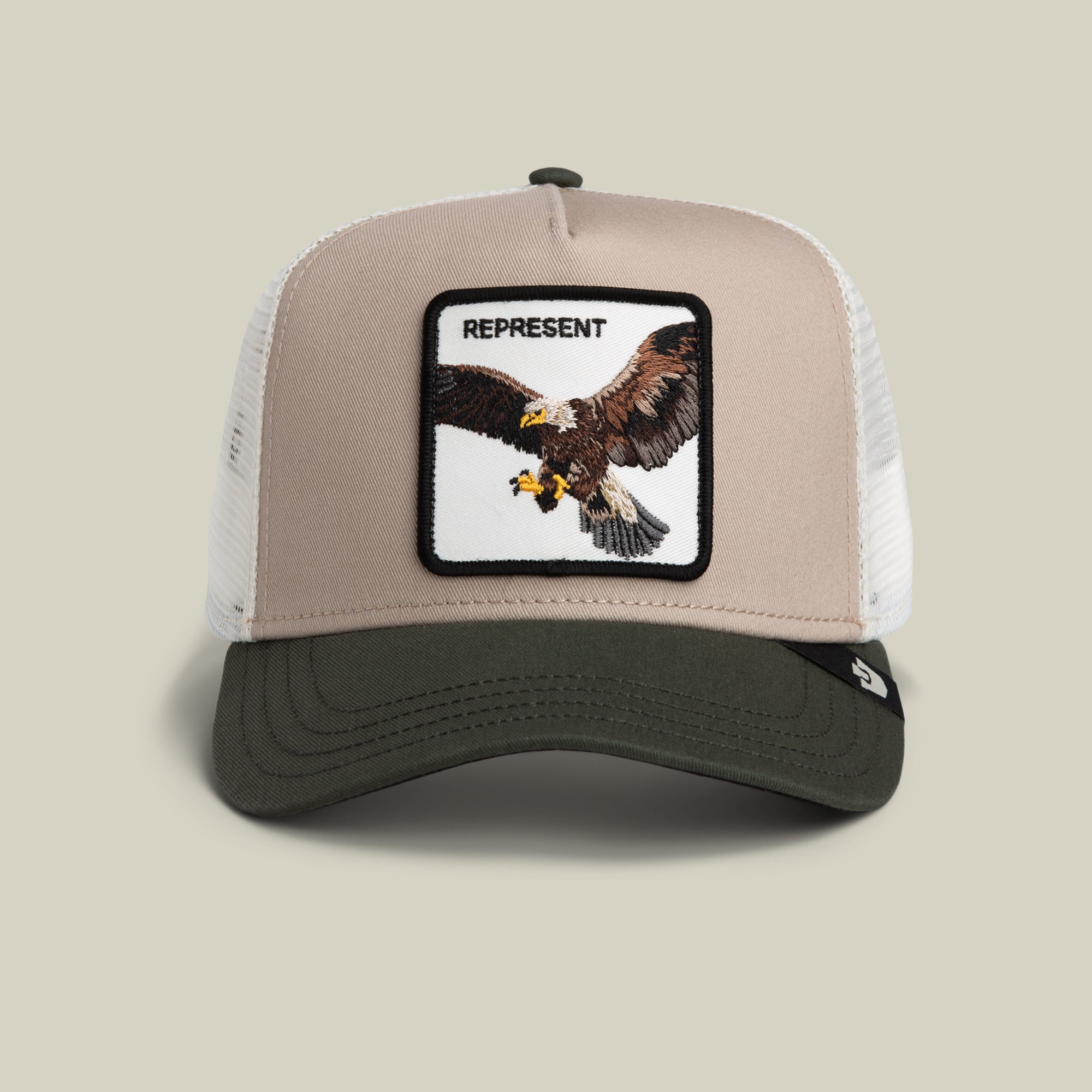 The Goorin Bros. Represent Eagle Trucker features a multi-color design with bold lettering and an eagle patch for a timeless look.