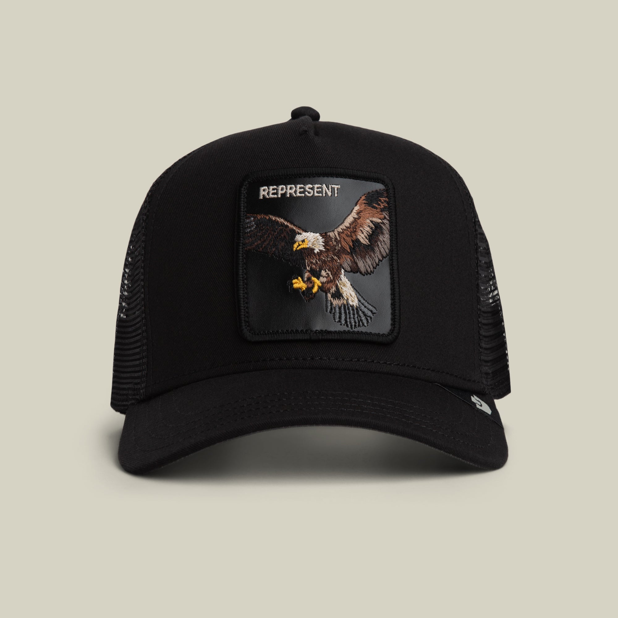 The Represent Eagle Trucker by Goorin Bros. in VOID features classic trucker style with a black mesh build and an eagle front patch, topped with "REPRESENT" embroidery. Shown against a neutral background.