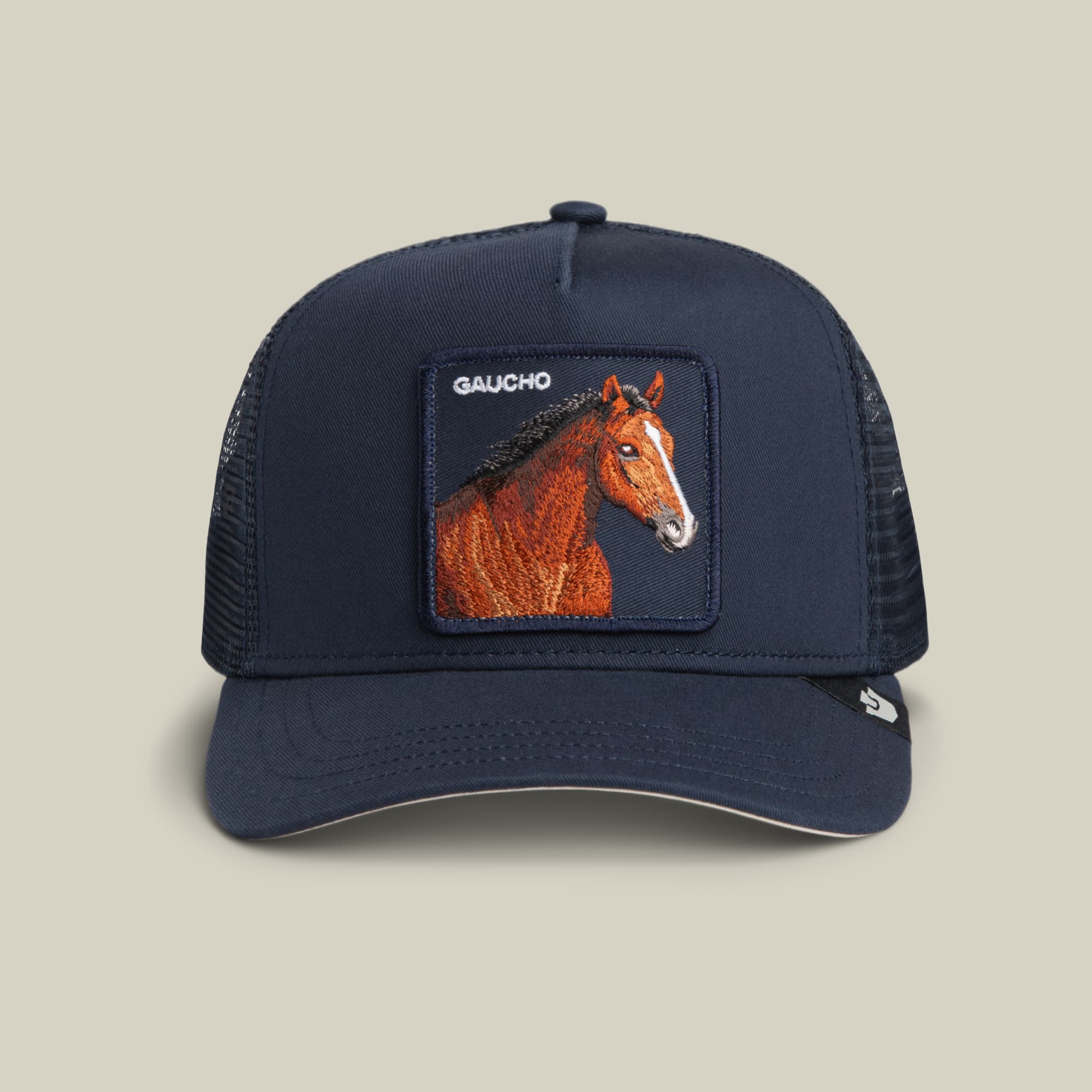 The Gaucho Trucker by Goorin Bros. is a navy trucker hat featuring a mesh back and an earthy-toned front patch with an embroidered horse and “GAUCHO” above it, creating a timeless, rugged style.