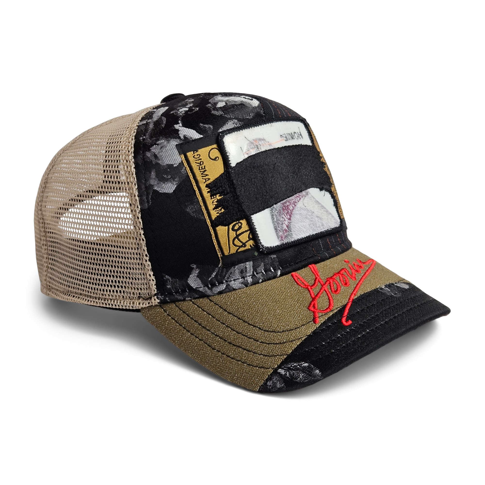 The Goorin Bros. Goorin Rework Trucker is a limited edition hat with a tan mesh back, black and olive panels, patchwork designs, floral patterns, and red embroidered text on the brim.