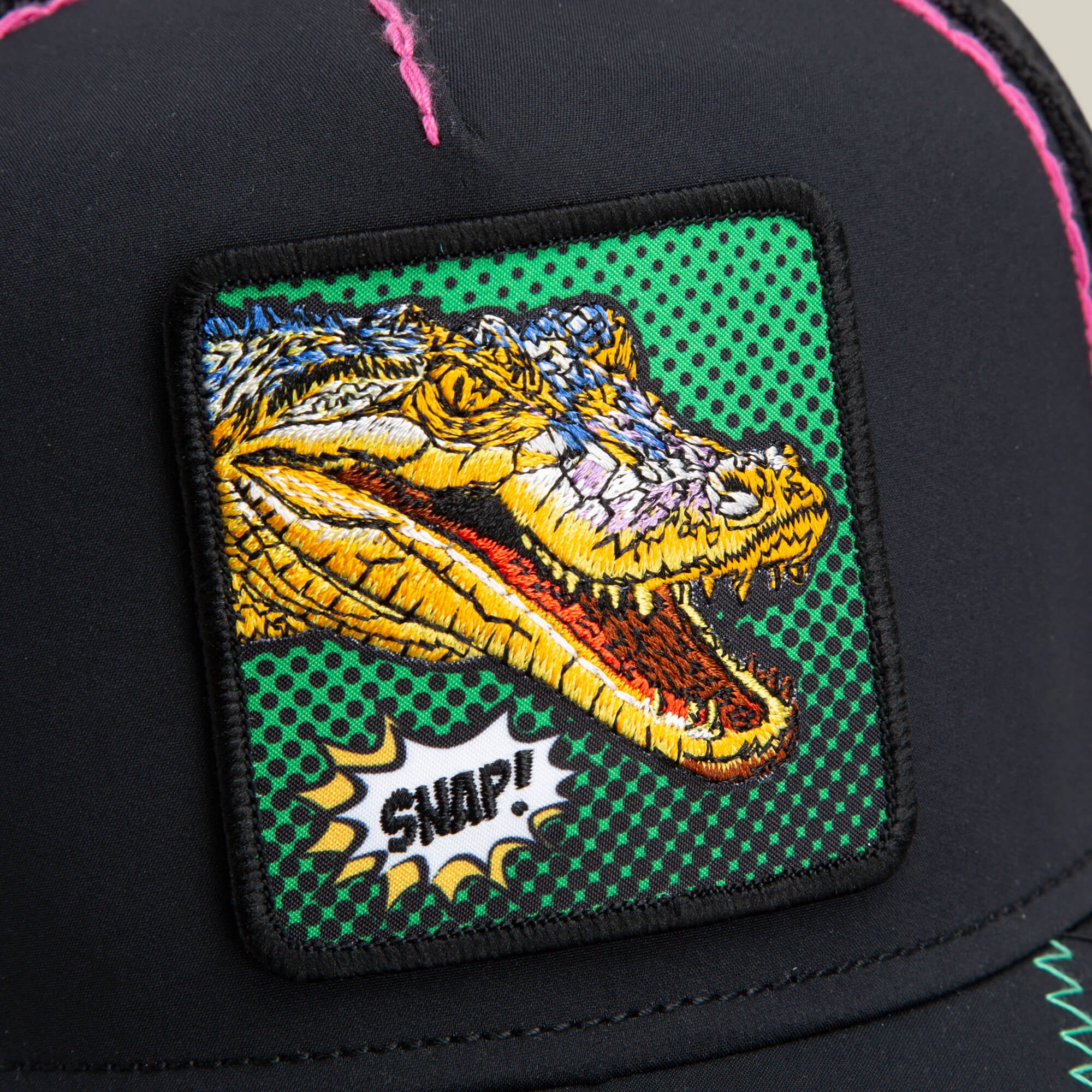 A close-up of the Goorin Bros. "Crackle and Pop, Brother" black cap, featuring a vibrant Pop Art gator patch with a colorful embroidered crocodile head and the word SNAP! on a green dotted background.