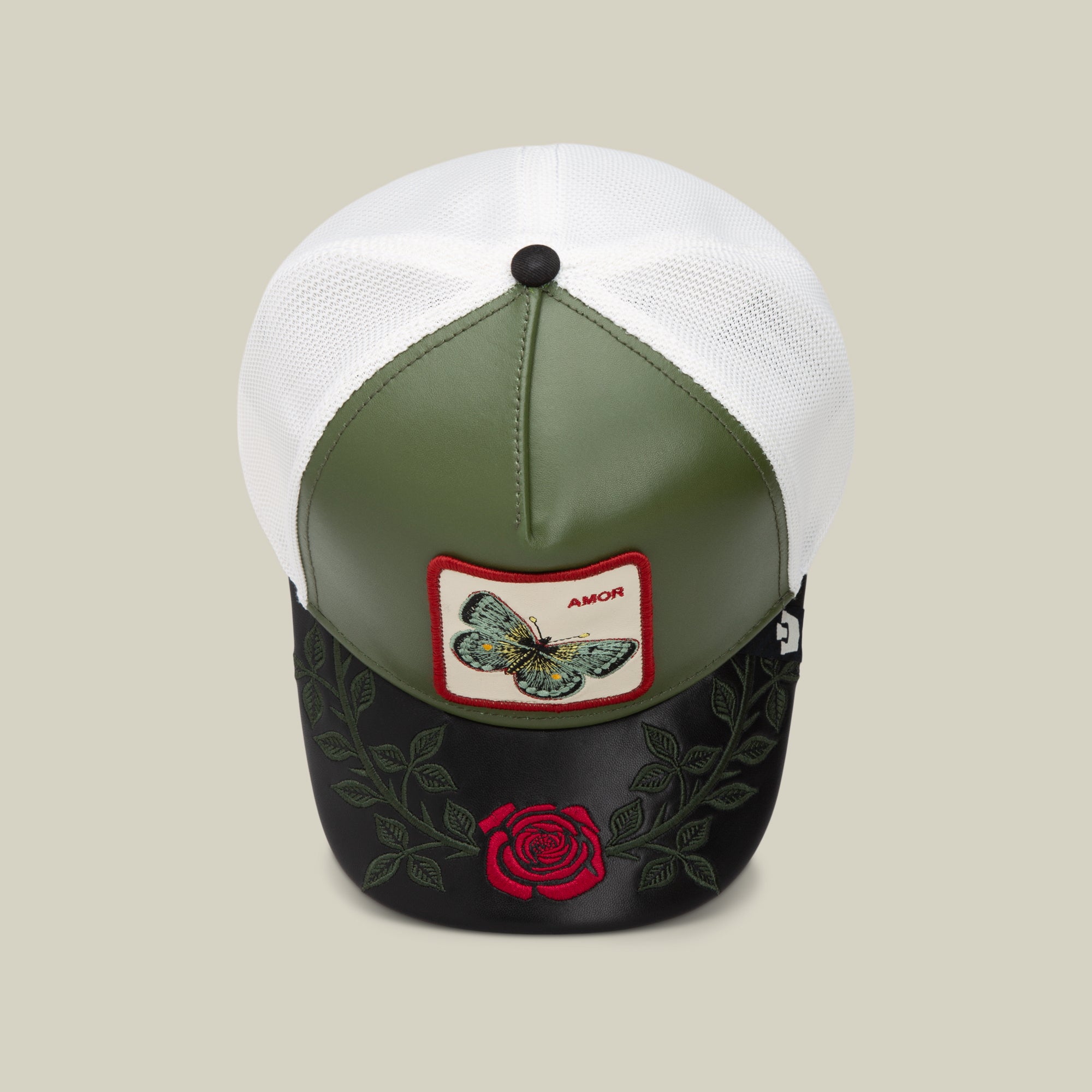 The Amor cap by Goorin Bros. features a green and black front, white mesh back, butterfly patch labeled "AMOR," and embroidered roses on the brim—perfect to pair with your favorite AMOR jewelry or love necklace.