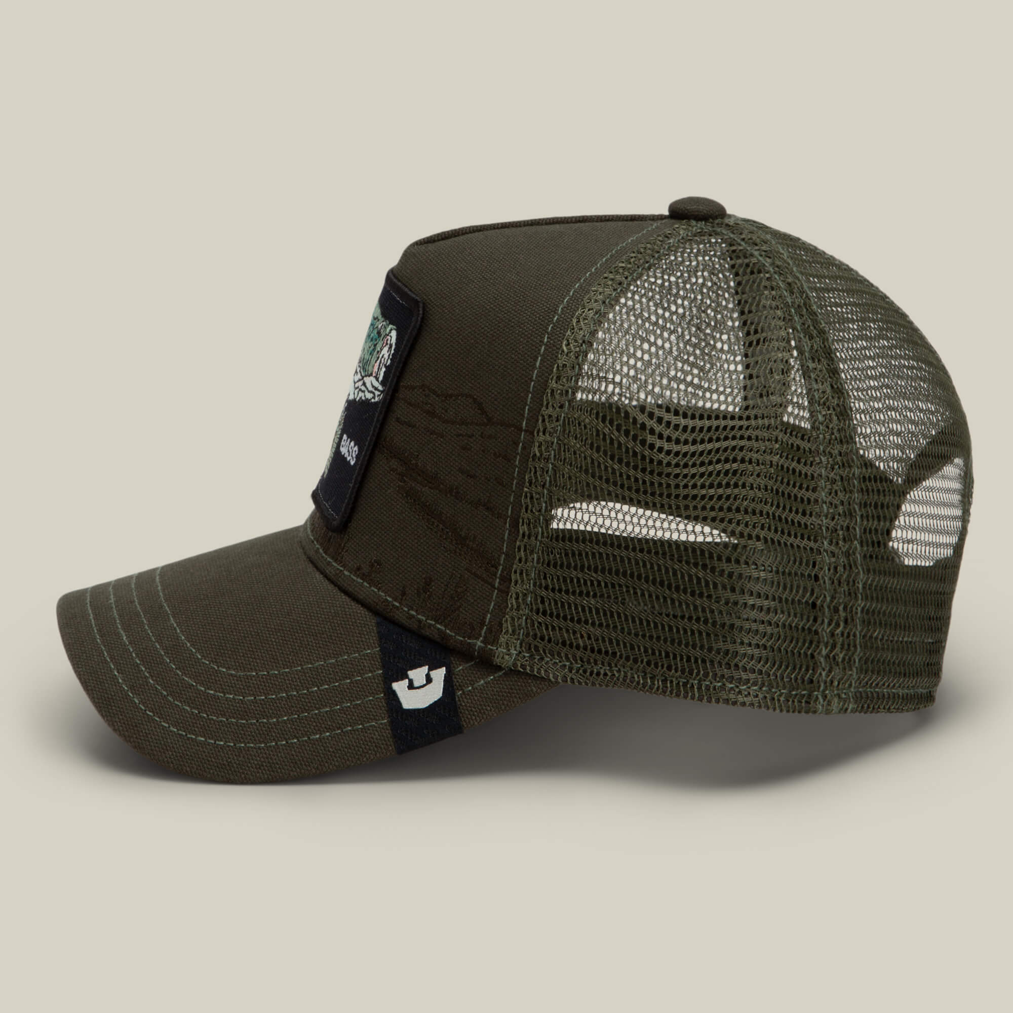 The Goorin Bros. Badlands Bass is an olive green trucker hat featuring a curved bill, breathable mesh back, and a front patch with embroidered details. It also includes a small black and white tag on the left side of the bill.