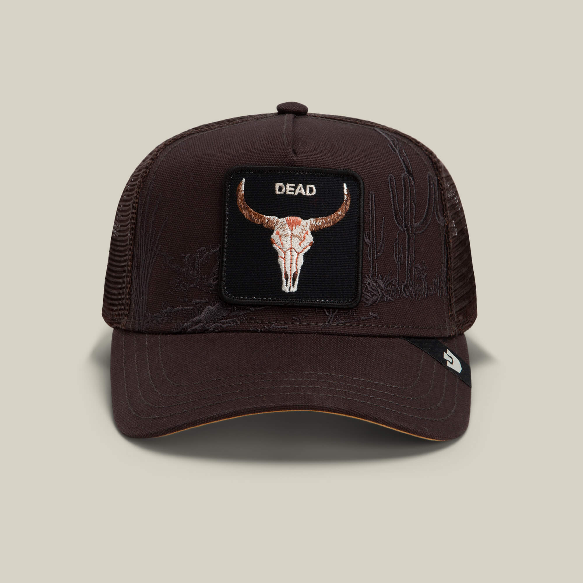 A "Ground" colored mesh trucker hat from Goorin Bros. called the Badlands Skull, featuring a front patch with a bull skull and the word DEAD, with subtle embroidered cactus illustrations on the cap.